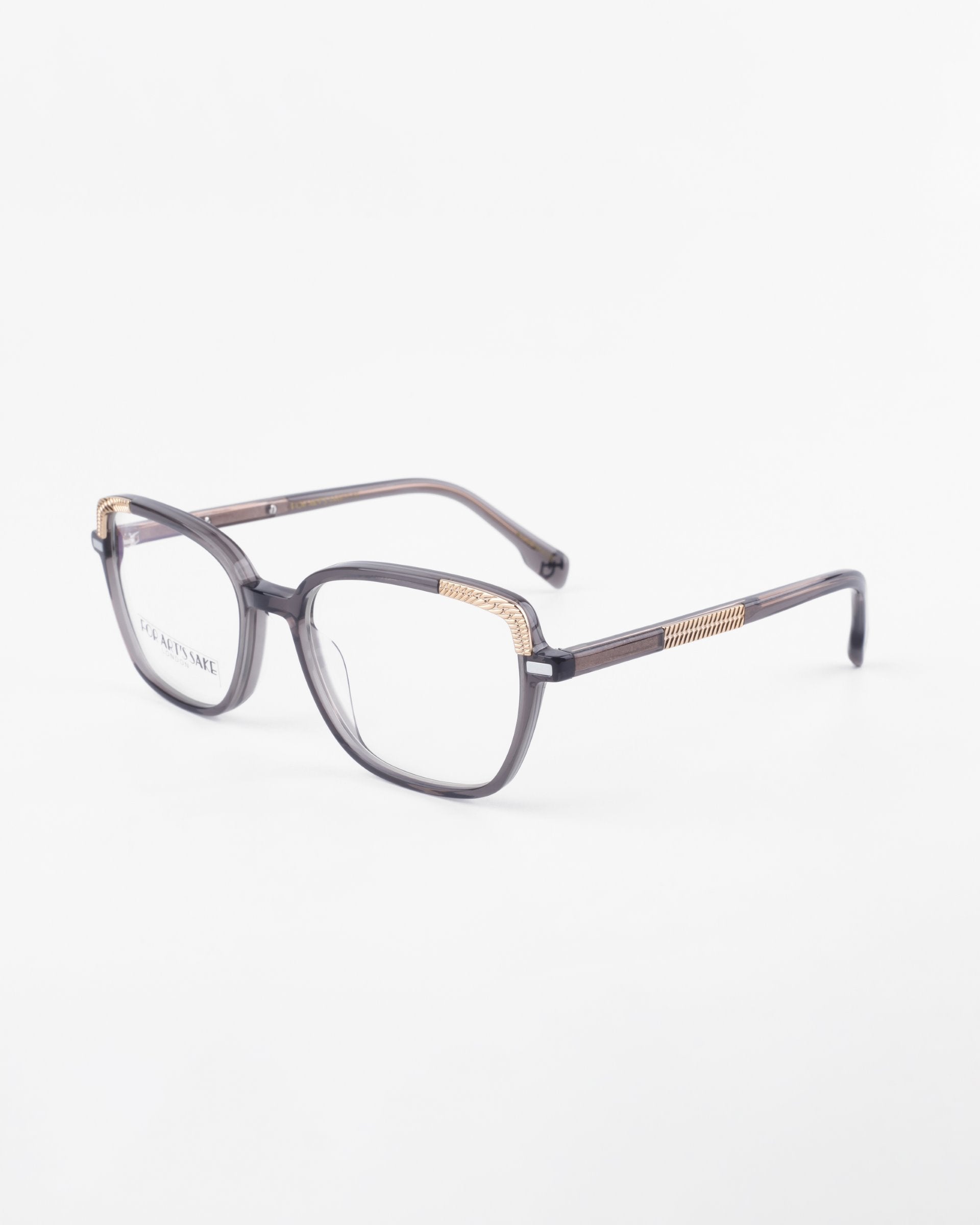 A pair of For Art&#39;s Sake® Mimosa eyeglasses with sleek dark frames and 18-karat gold-plated accents along the temples. The design is modern with a subtle elegance, ideal for both professional and casual wear. Featuring clear lenses with a blue light filter, the overall style is contemporary.