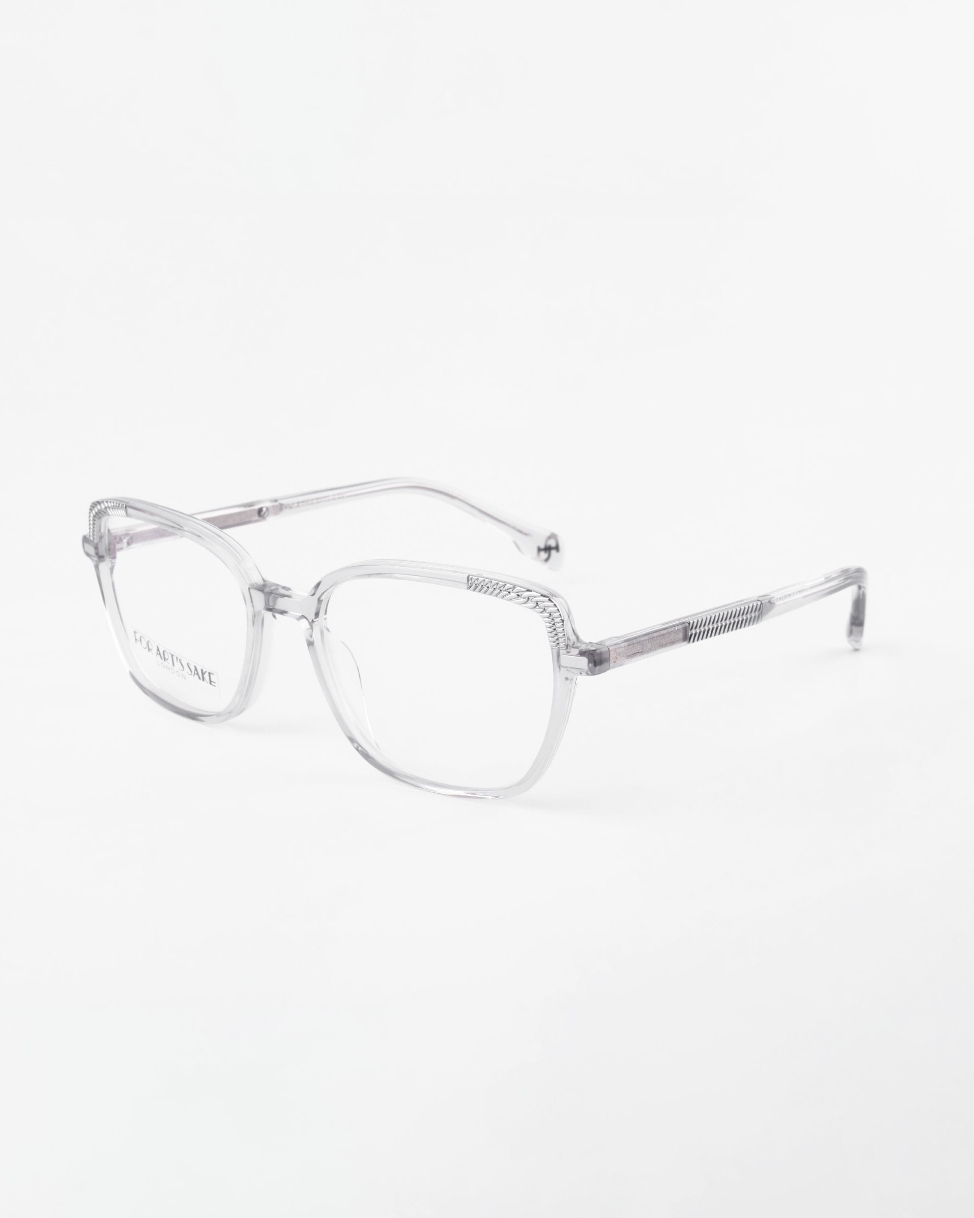 A pair of For Art&#39;s Sake® Mimosa clear, rectangular eyeglasses with thin, transparent frames. The prescription lenses are also clear, and the temples are adorned with striped detailing near the hinges. Accented by 18-karat gold-plated touches, the glasses are positioned against a white background.