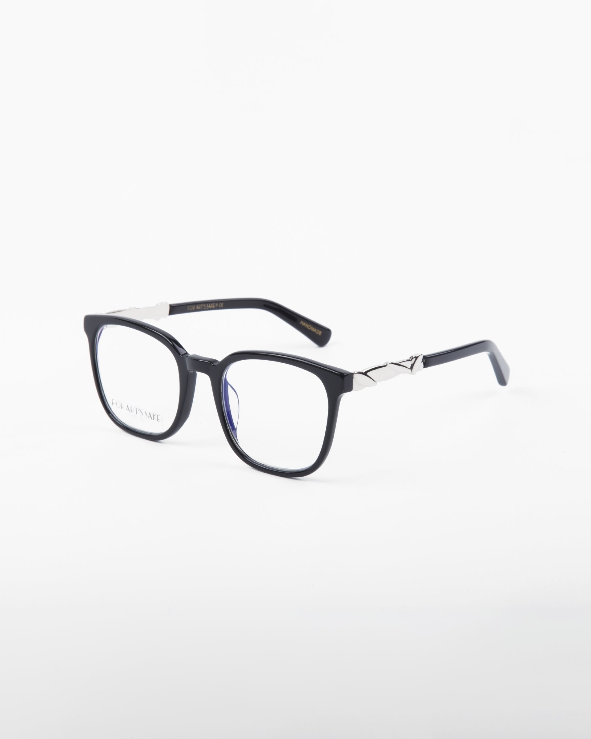 A pair of Molten by For Art&#39;s Sake® black-rimmed eyeglasses with square lenses is displayed on a white background. These prescription eyewear glasses feature metallic accents on the temples, adding a touch of style and elegance to the design.
