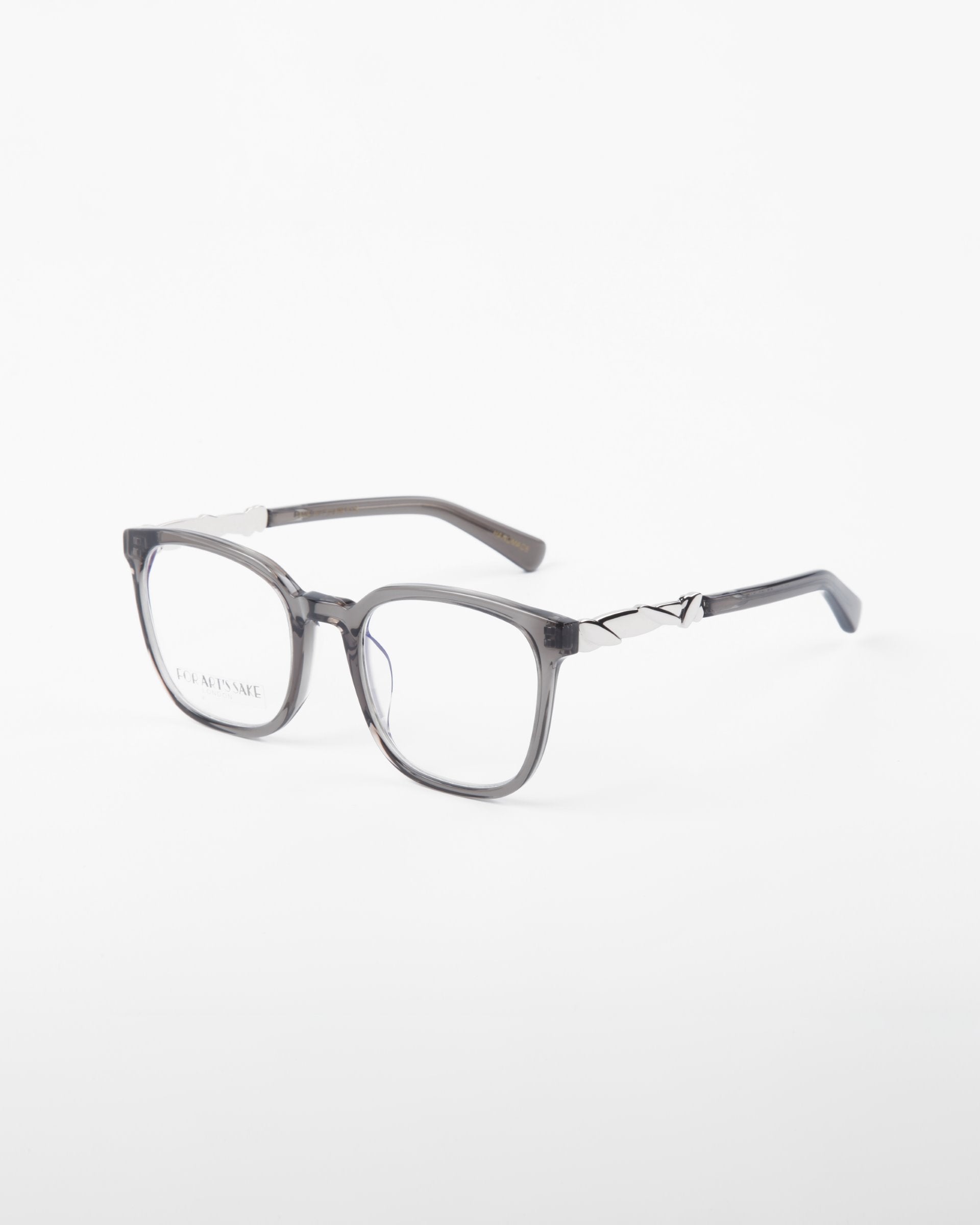 A pair of gray square eyeglasses made from plant-based acetate with a subtle transparent frame and silver accents on the temples. These stylish Molten prescription eyewear glasses by For Art&#39;s Sake® are displayed against a plain white background.