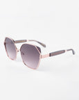 A pair of stylish Montage sunglasses from For Art's Sake® with a rose gold frame and gradient dark lenses, offering 100% UVA & UVB protection. The glasses have geometric, slightly squared lenses and sleek arms with dark tips. Made from gold-plated stainless steel, their design is modern and elegant. The background is plain white.