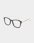 A pair of eyeglasses with matte black rectangular frames and thin metallic gold temples. The ends of the temples are rounded for added comfort. Made with stainless steel frames, these glasses also feature a blue light filter. Displayed on a clean white background, this is the Morris by For Art's Sake®.