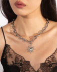 A woman is wearing the Crescent Moon Necklace from For Art's Sake®, featuring a celestial-inspired sun-shaped pendant crafted with intricate detail. She is dressed in a black lace top. The image focuses on her neck and collarbone, showcasing the stunning jewelry and the delicate lace patterns of her top.