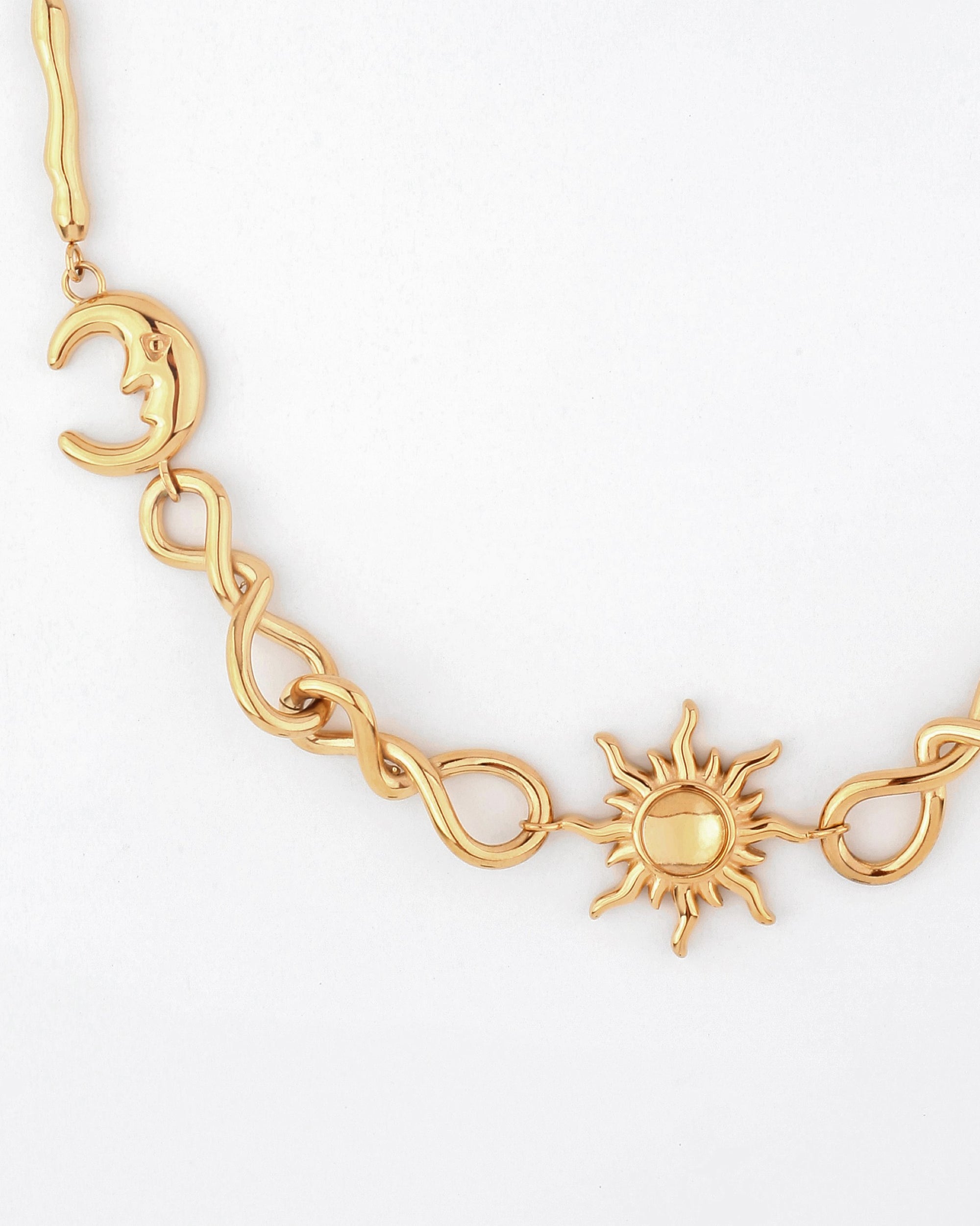 The Sloane Necklace by For Art&#39;s Sake® features a gold crescent moon charm, intertwined loops, and a radiant sun pendant. These elements are connected by an elegant adjustable chain of linked twists with a white backdrop, allowing you to customize the necklace length to your measurements.