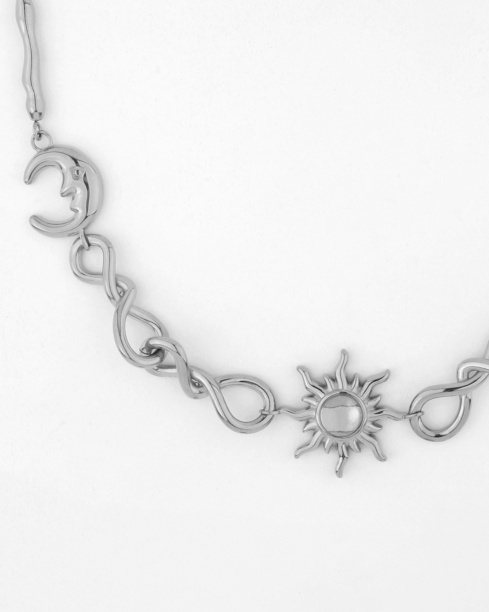 Introducing the Sloane Necklace by For Art&#39;s Sake®: a stunning silver pendant that features a crescent moon on the left and a sun with wavy rays at its center. The chain is made up of twisted links connecting the moon and sun, with an intricate intertwined design in between, along with an adjustable extension chain for customizable length.