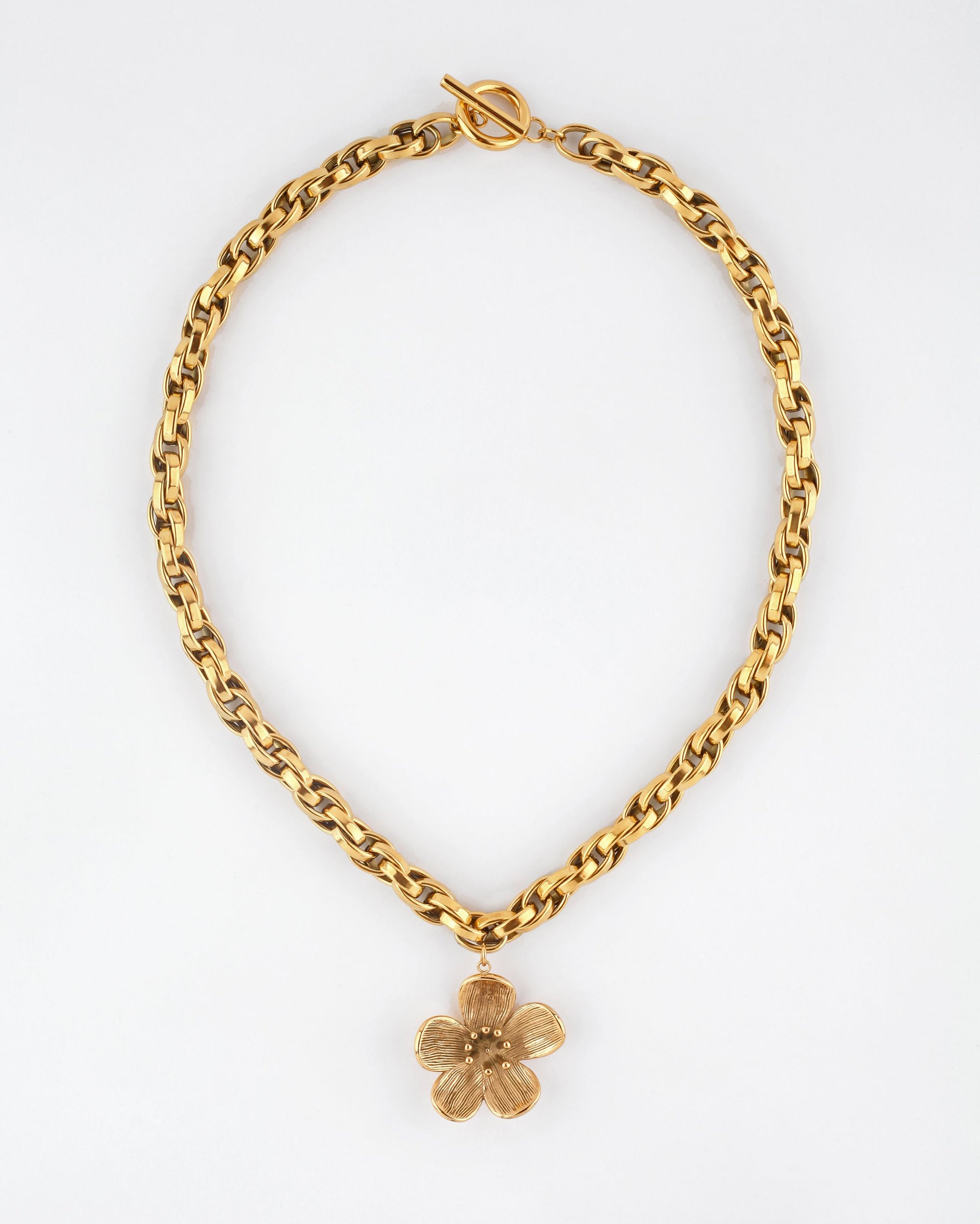 The For Art's Sake® Blossom Necklace showcases a striking gold chain with a rounded link design, adorned at the center with an eye-catching large, gold five-petaled flower charm. Measuring 46cm in length, this necklace features a distinctive T-bar clasp and is set against a plain white background.