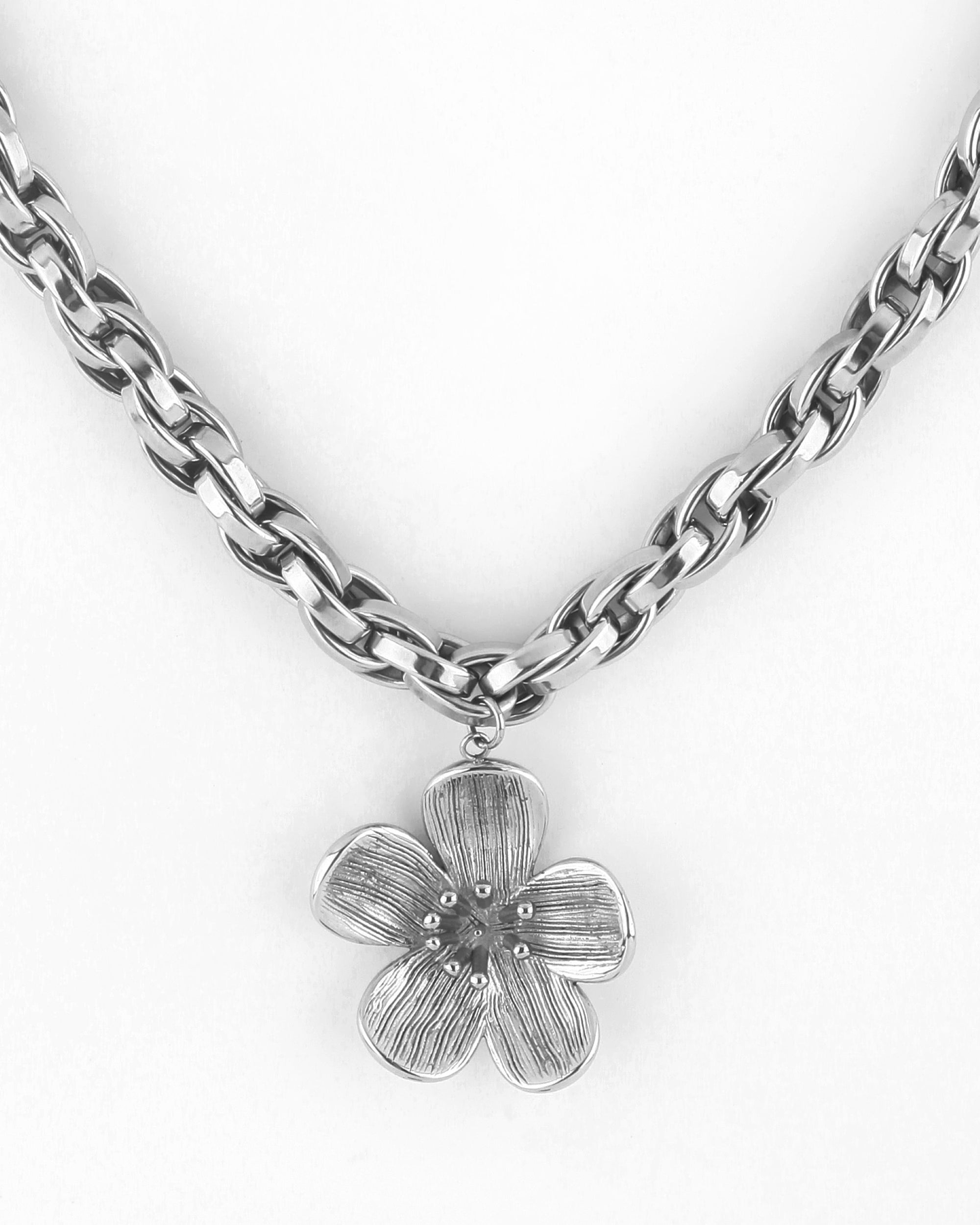 Introducing the Blossom Necklace by For Art&#39;s Sake®: a stunning silver chain necklace featuring a flower-shaped pendant. The five-petal pendant boasts intricate texture and a subtle shine, hanging gracefully at the center of the 46cm chain. This exquisite piece is designed to perfectly complement any outfit.