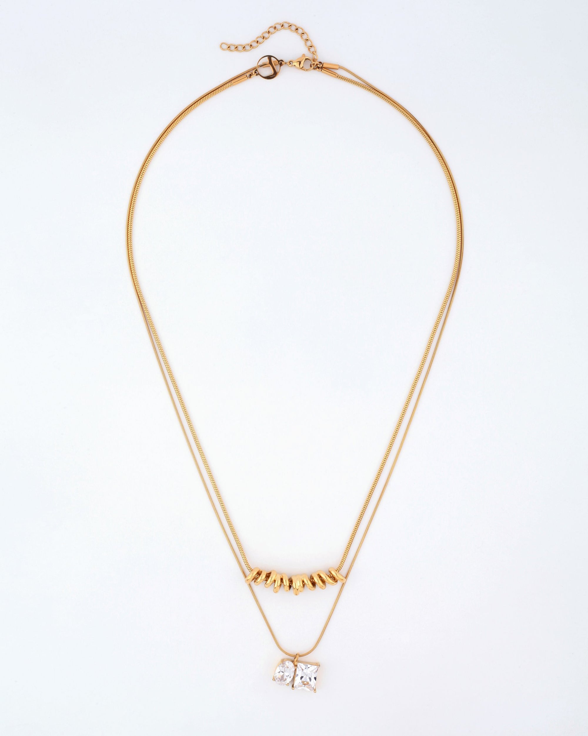 Introducing the Nora Necklace by For Art&#39;s Sake®: A delicate double-layered masterpiece showcased on a pristine white background. The upper layer is adorned with a row of dainty gold triangular charms, while the lower layer features a pendant with two square crystals set side by side. This elegant necklace boasts a thin gold chain complete with an adjustable clasp and extension chain for versatile length adjustments.