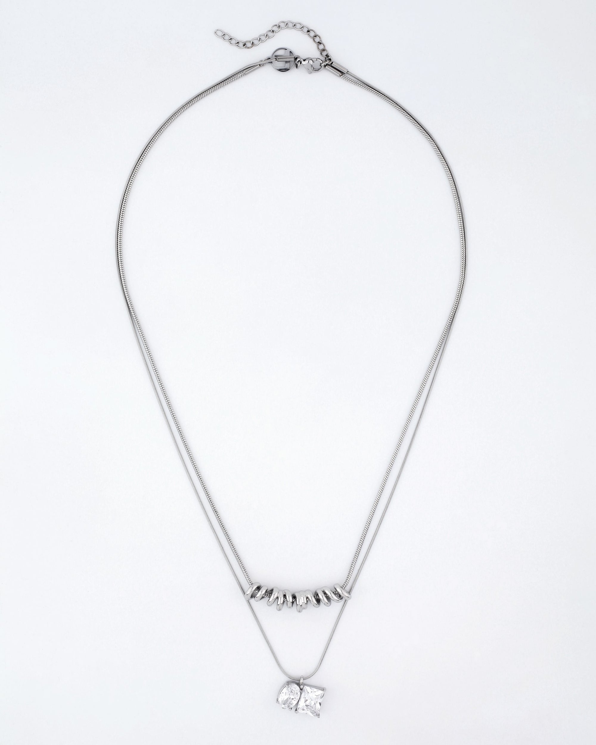 Introducing the Nora Necklace by For Art's Sake®: A stunning silver double-chain piece adorned with a cubic zirconia pendant. The upper chain is elegantly accented with small silver beads, while the lower chain boasts a striking square-shaped crystal charm. This adjustable necklace also features an extension chain, allowing you to effortlessly customize the inner length to your preference.