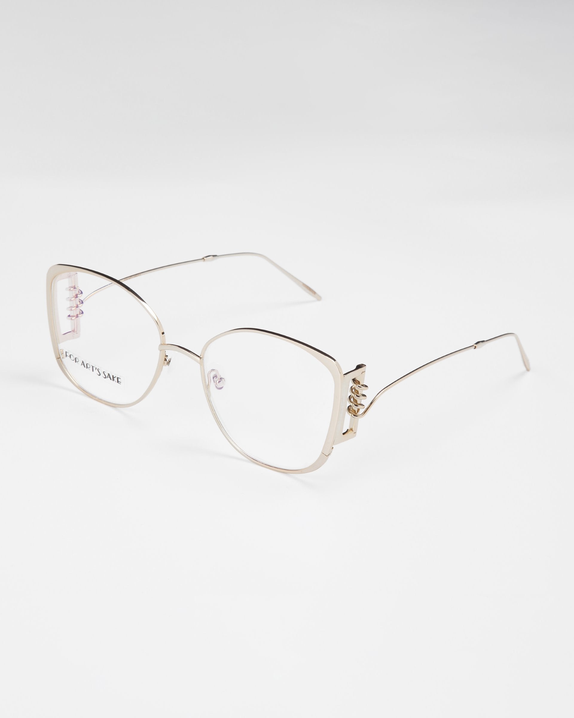 A pair of stylish eyeglasses featuring large, square metal frames with thin temples is displayed against a plain white background. The Jupiter by For Art&#39;s Sake® frames have a minimalist design with subtle decorative accents on the hinges and come with an optional blue light filter for enhanced eye protection.