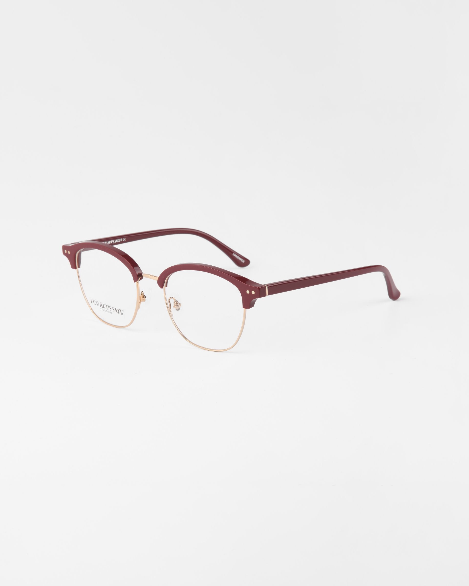 A pair of For Art&#39;s Sake® Painkiller eyeglasses with a gold wireframe and maroon-colored browline and earpieces, placed on a plain white background. The clear lenses include UV protection, enhancing the modern, sophisticated design.