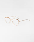 A pair of For Art's Sake® Smoothie golden, wireframe glasses with clear lenses and 18-karat gold plating. The frames are lightly structured with subtle design elements, offering elegant simplicity. The background is a plain white surface, emphasizing the refined details of these stylish glasses.