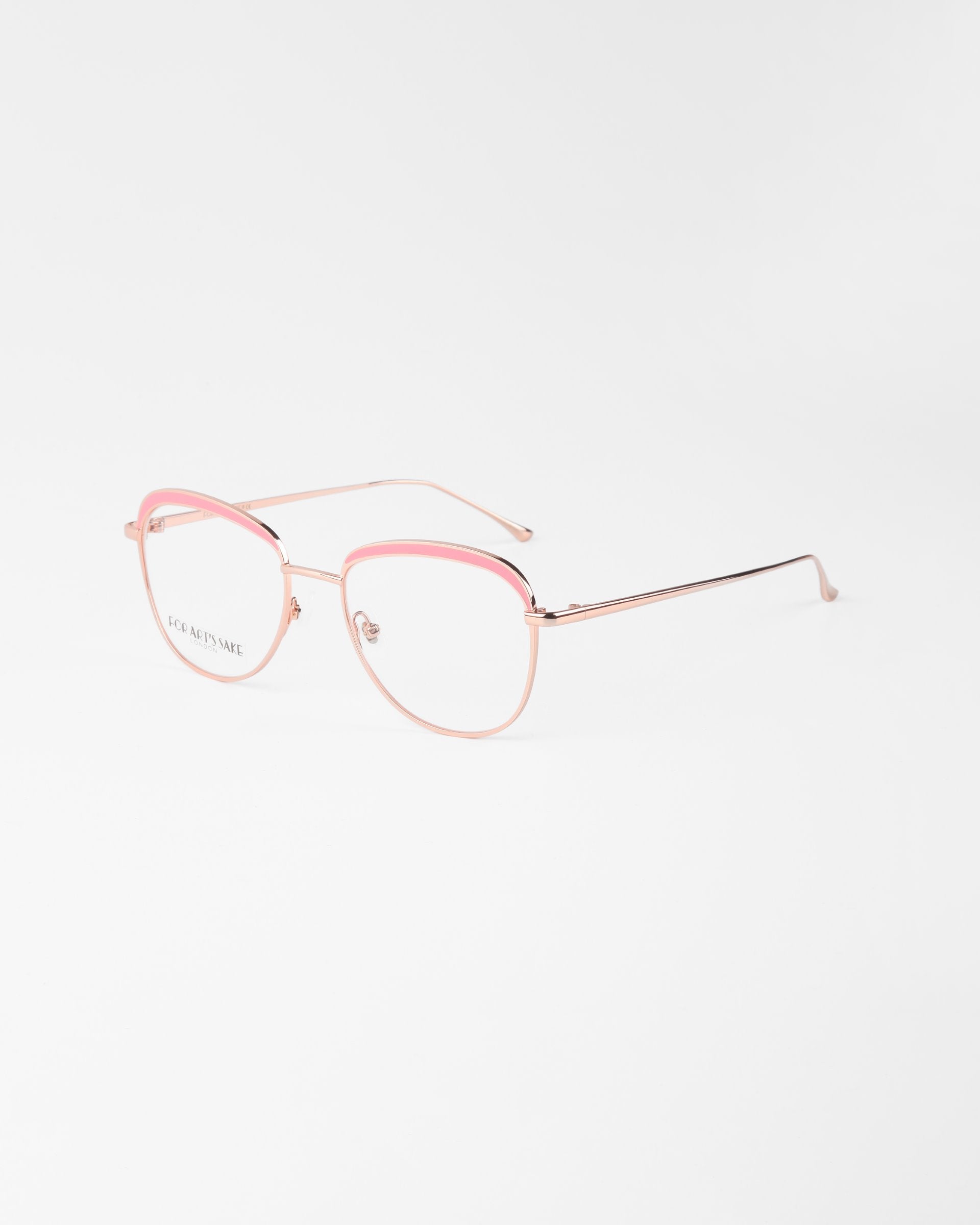 A pair of eyeglasses with delicate pink metal frames. The Smoothie by For Art&#39;s Sake® features rounded lenses with blue light filter technology and a thin bridge, with the temples extending gracefully from the hinges. The overall design is sleek and minimalist, set against a plain white background.
