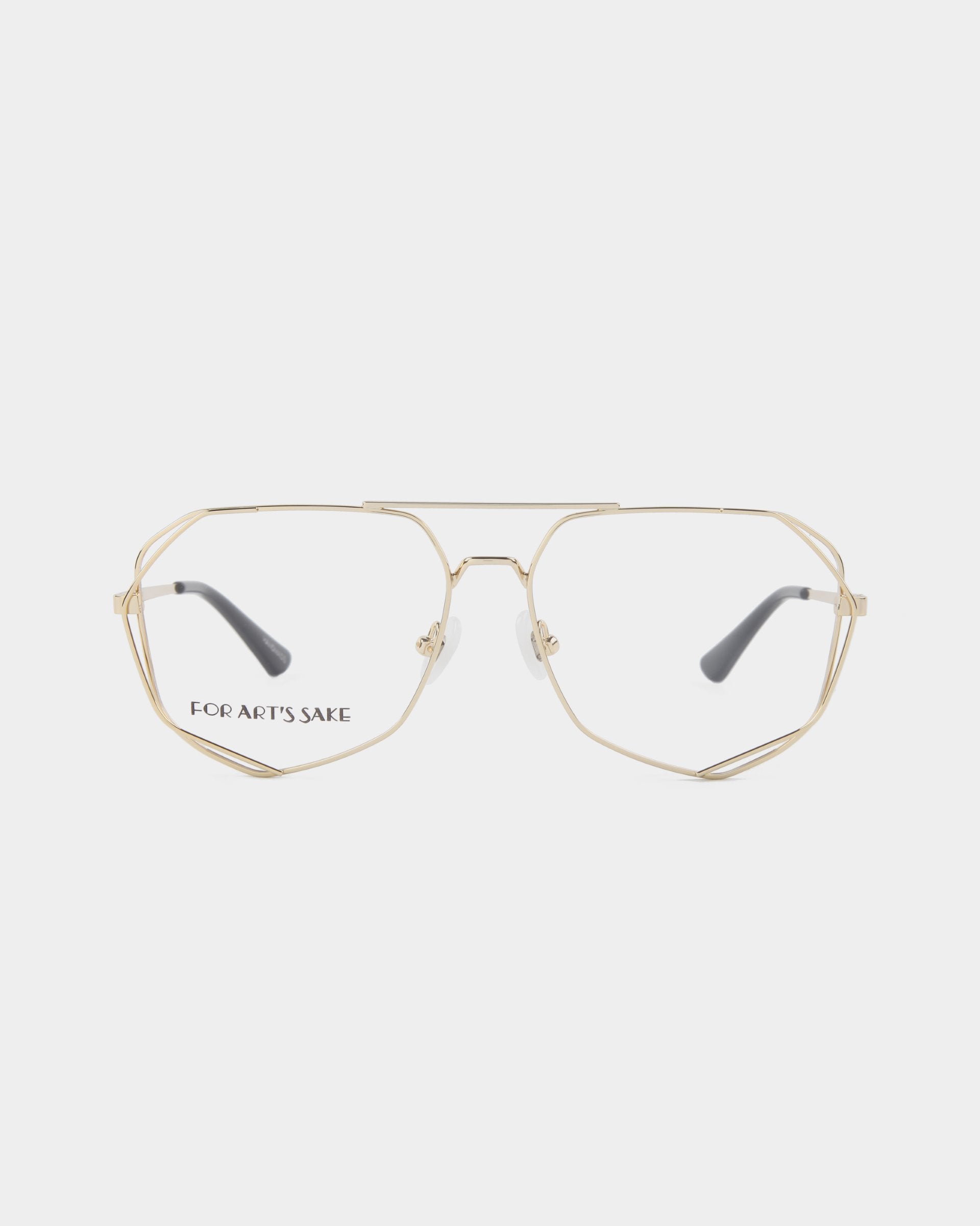 A pair of geometric gold wire-frame eyeglasses with clear lenses, featuring hexagonal rims and black temple tips. The brand name &quot;For Art&#39;s Sake®&quot; is inscribed in black on the inside of the left lens. Crafted with stainless steel frames, they come with an optional Blue Light Filter. The product name is Genius. Background is plain white.