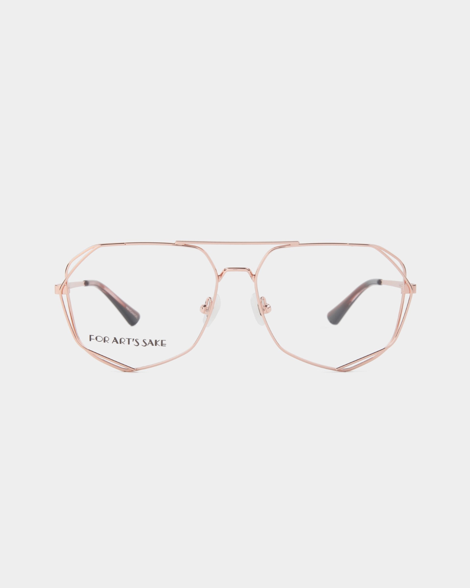 A pair of stylish, rose-gold wireframe eyeglasses with oversized geometric lenses. The stainless steel frames by "For Art's Sake®" are printed in black on the left lens. The design features a thin double bridge and transparent nose pads for comfort. The background is white. 

Product Name: "Genius"
Brand Name: "For Art's Sake®"
