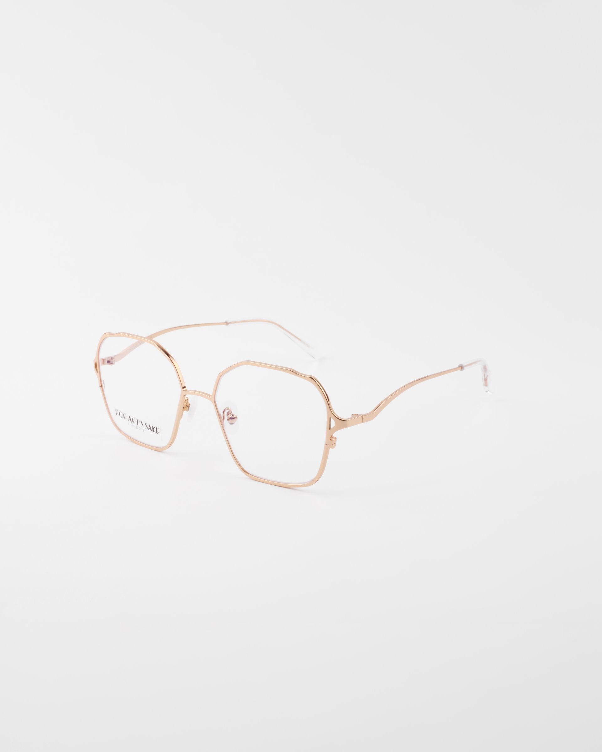 A pair of For Art&#39;s Sake® Mimi eyeglasses with thin, 18-karat gold-plated metal frames and slightly geometric lenses. The glasses are positioned at an angle on a white background, showcasing the streamlined arms and clear lenses.