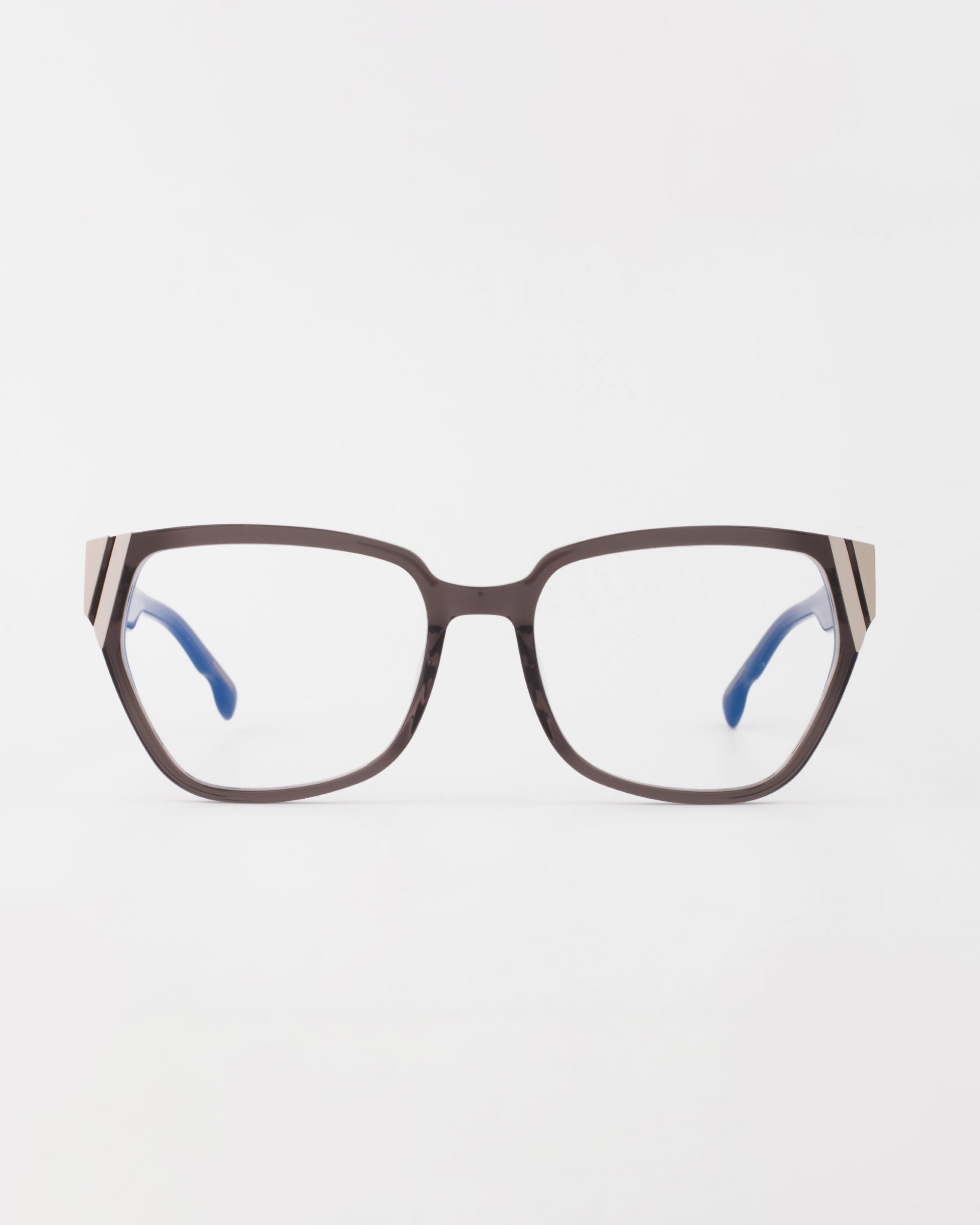 The Below Zero eyeglasses by For Art's Sake® combine a square brown frame with blue temples and beige-black striped hinges, offering a modern unisex style that stands out against a white backdrop.