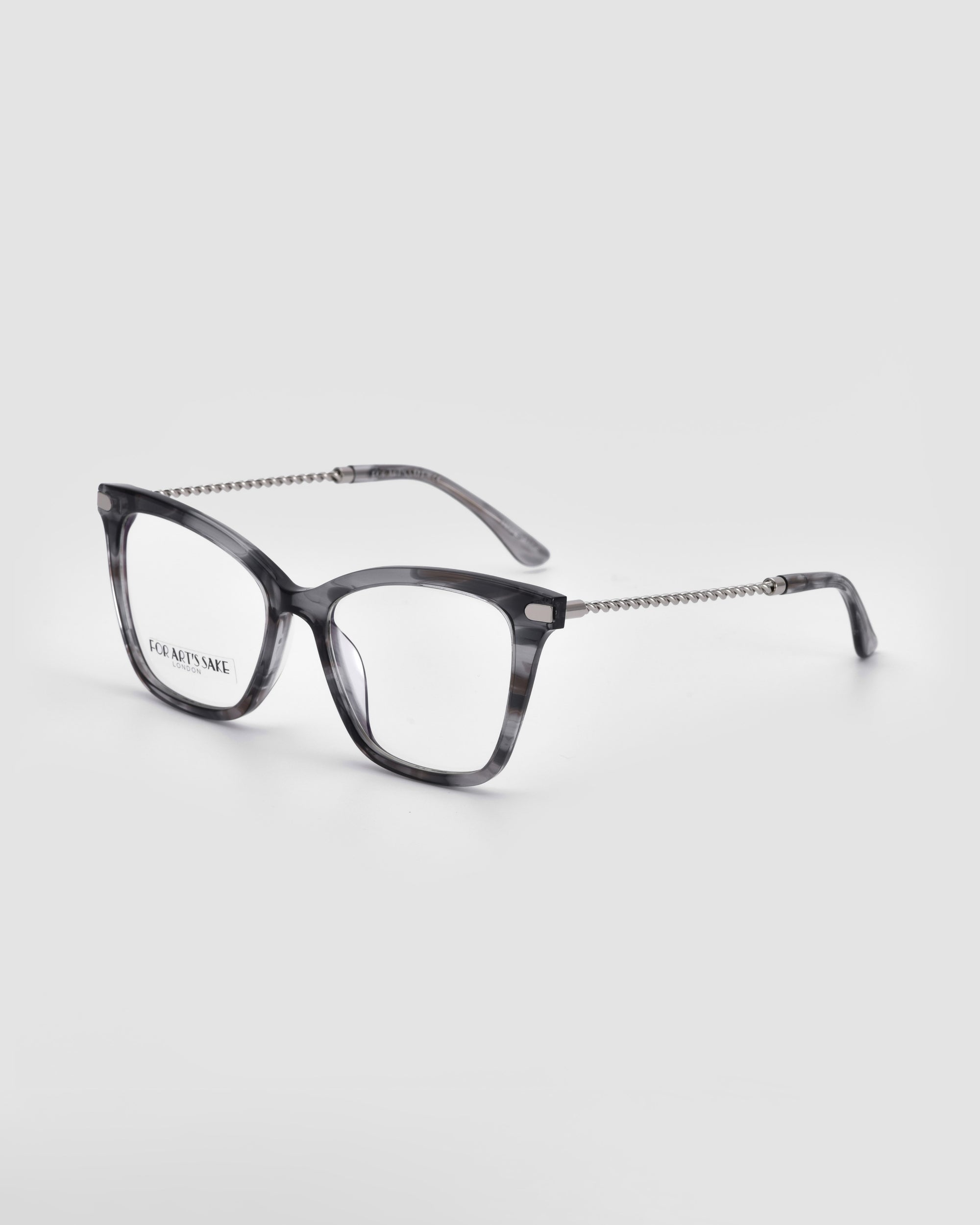 A pair of eyeglasses with translucent gray and black marbled frames is displayed against a plain white background. The temples feature a chain-like design, reminiscent of cat eye-inspired optics. The brand name &quot;For Art&#39;s Sake®&quot; is visible on the inside of the left lens, highlighting the elegant &quot;Paris Two&quot; model.