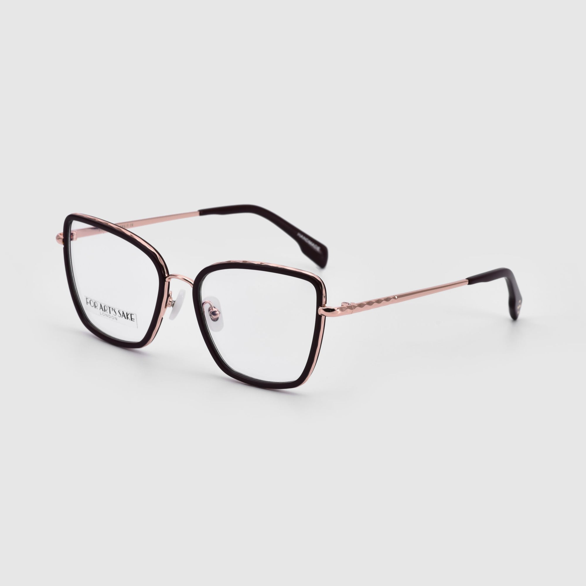 A pair of For Art&#39;s Sake® Lace eyeglasses featuring thin, metallic rose gold frames with black rims around the prescription lenses. The temples showcase a subtle braided design and conclude with black earpieces. The glasses are positioned with the lenses facing forward against a plain white background.