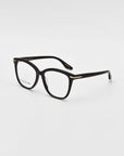 A pair of black For Art's Sake® Cadenza optical glasses with rounded rectangular lenses and gold accents on the hinges. The glasses are placed at an angle on a clean, white background.