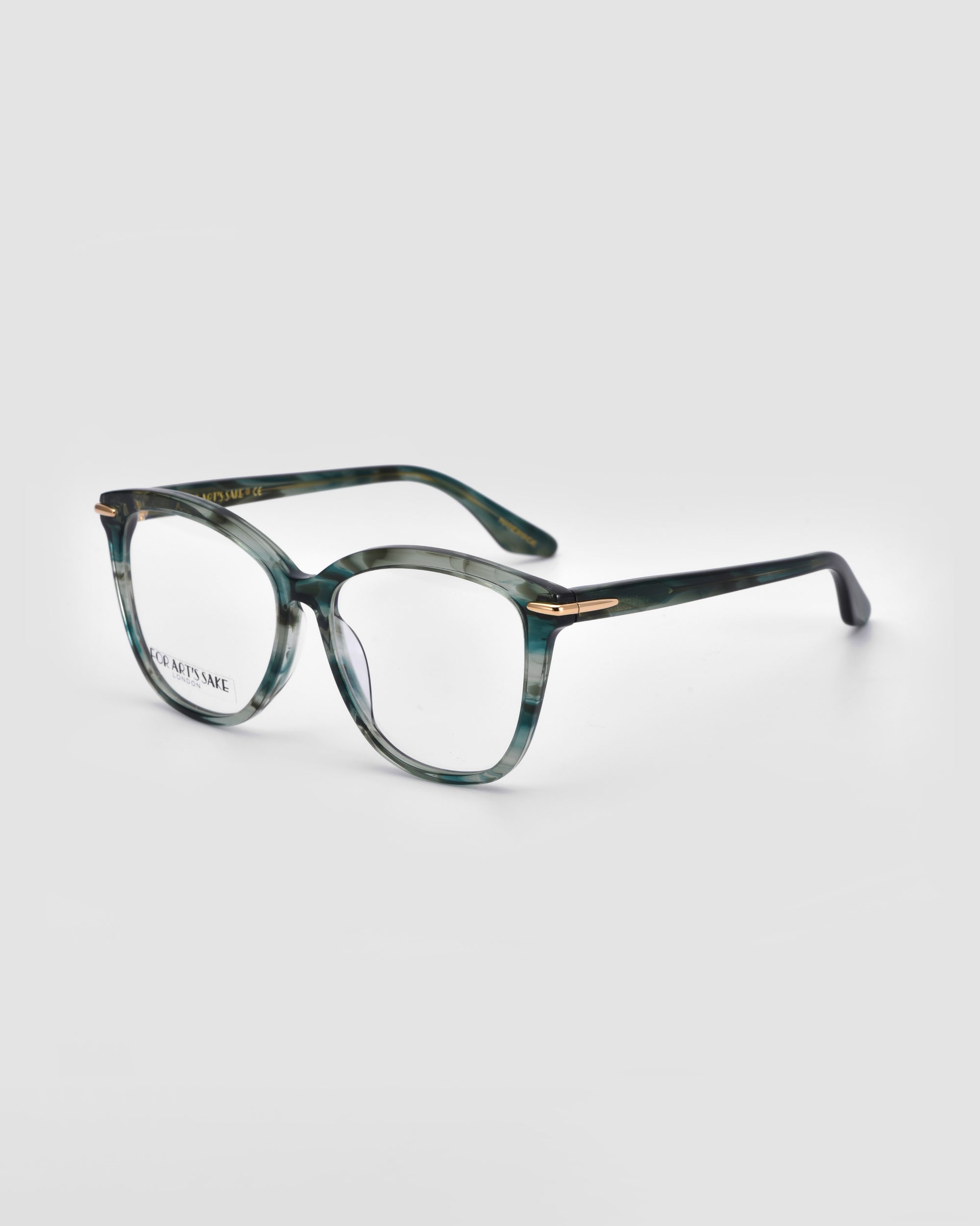 A pair of Cadenza optical glasses by For Art's Sake® with a green tortoiseshell pattern on the frames and gold accents at the hinges, showcasing a chic cat-eye silhouette, slightly angled to the right, set against a plain white background.