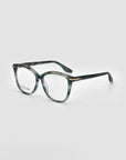 A pair of Cadenza optical glasses by For Art's Sake® with a green tortoiseshell pattern on the frames and gold accents at the hinges, showcasing a chic cat-eye silhouette, slightly angled to the right, set against a plain white background.