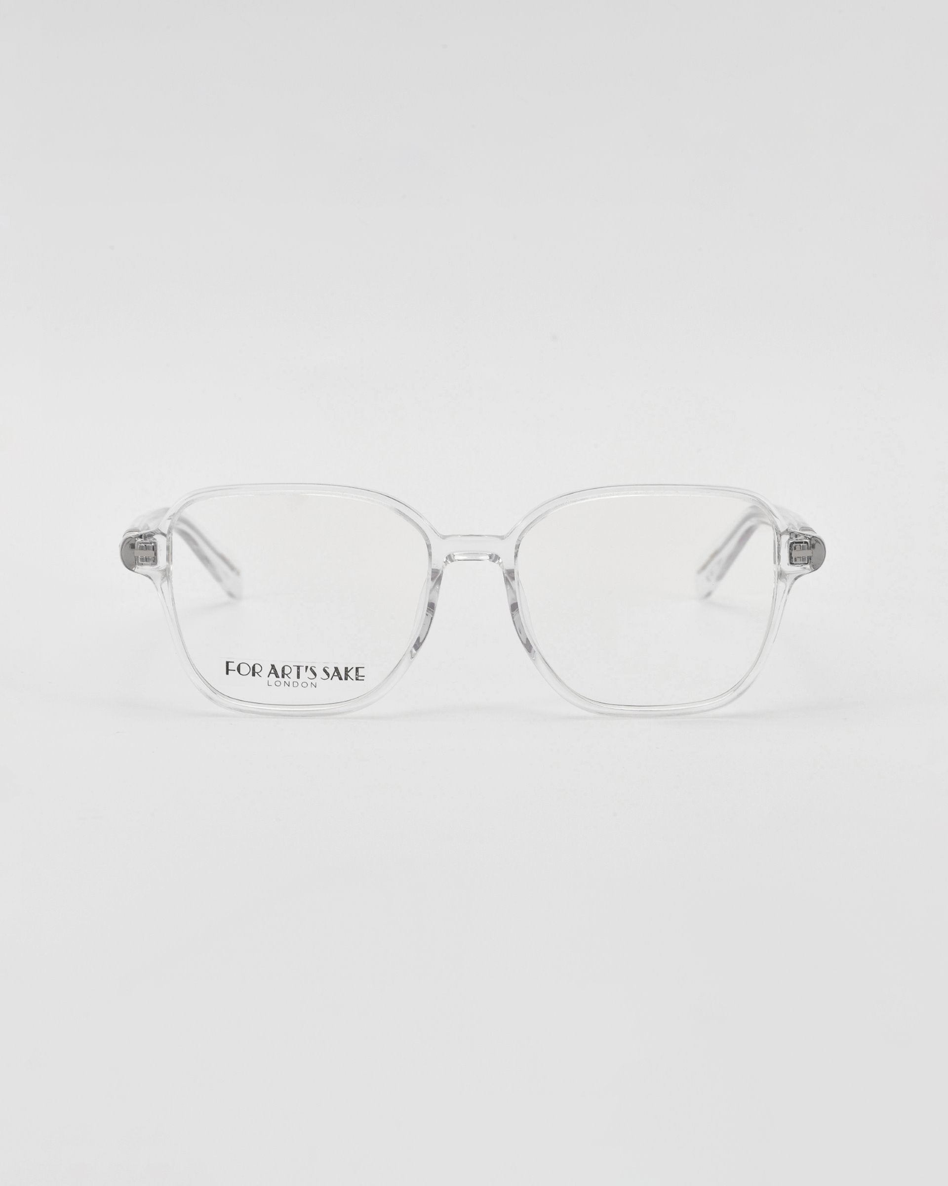 A pair of For Art&#39;s Sake® Charm transparent framed optical glasses in a cat-eye shape on a white background, with a visible brand name etched on one lens.