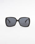 A pair of black, oversized square Odyssey sunglasses by For Art's Sake® with dark tinted, lightweight nylon lenses is displayed against a plain white background. The design is simple and modern, featuring thick frames made from plant-based acetate and wide arms.