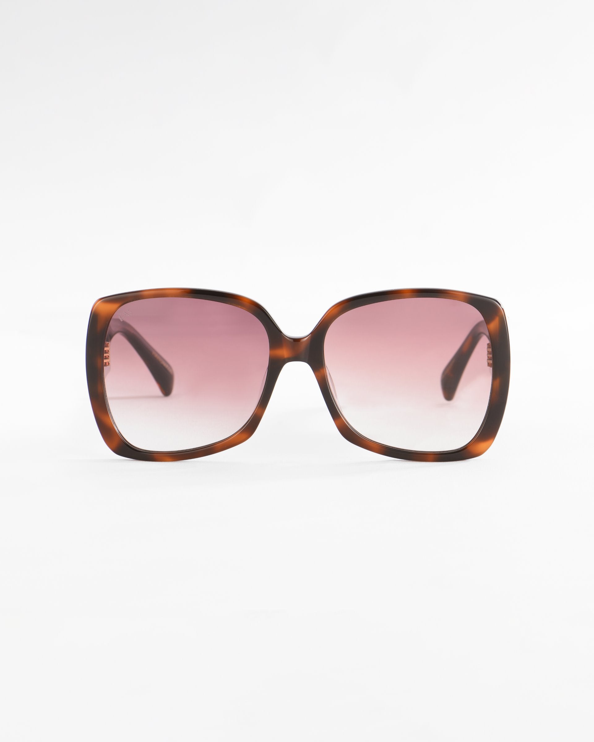 A pair of oversized, square-framed sunglasses with a tortoiseshell pattern made from plant-based acetate. The lightweight nylon lenses are tinted in a gradient, transitioning from dark to light pink. The background is plain and white. These are the Odyssey sunglasses by For Art&#39;s Sake®.