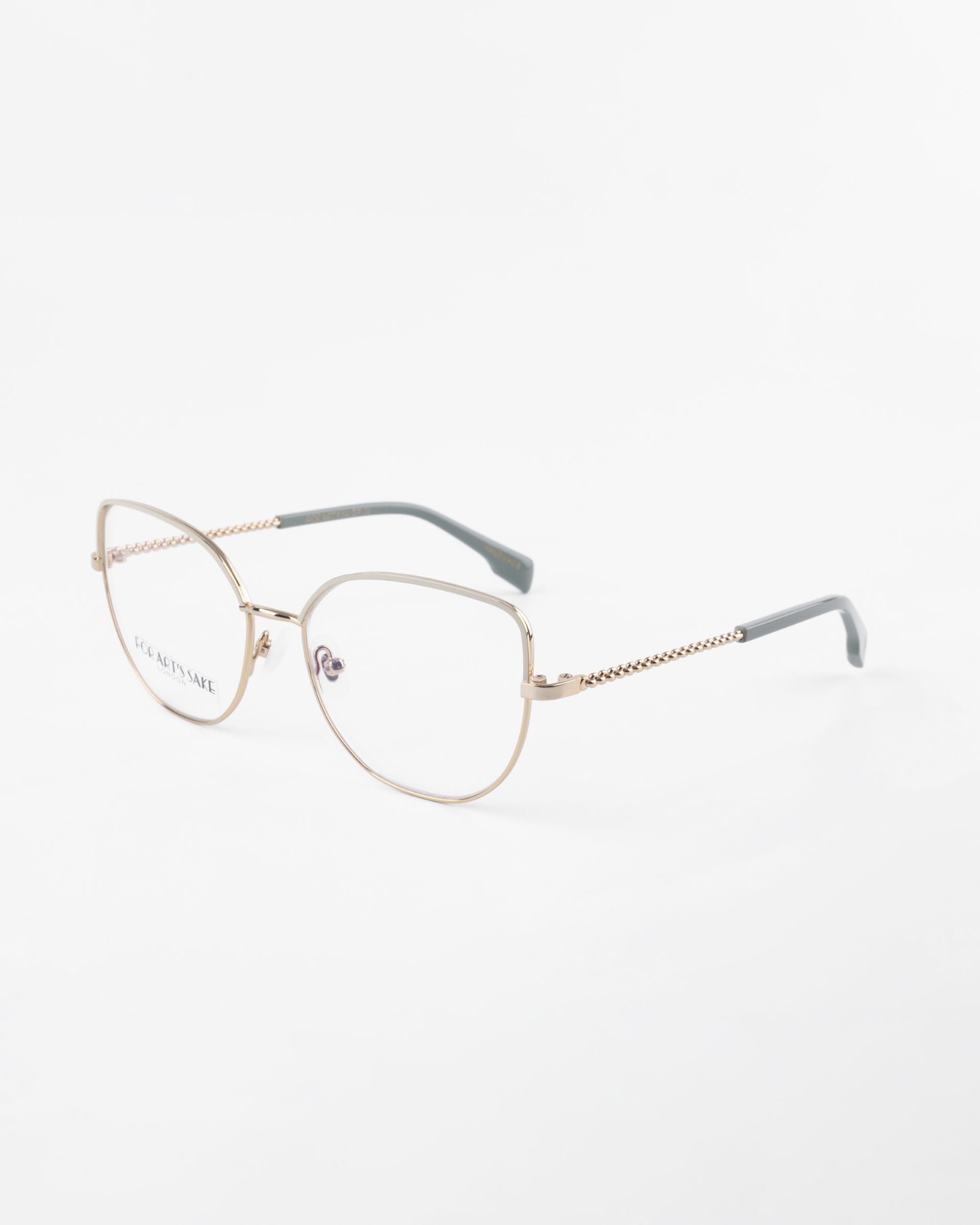 A pair of stylish For Art&#39;s Sake® Ophelia eyeglasses with thin, metallic gold frames and clear lenses. The arms of the glasses are gray and feature a subtle braided design near the hinges. The white background highlights the elegant and minimalist design of the eyewear, which also offers a blue light filter option for added protection.