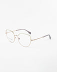 A pair of gold-rimmed Ophelia eyeglasses by For Art's Sake® with a slightly rounded square shape is shown against a plain white background. The glasses feature blue light filter lenses and a delicate chain-like design on the temples, transitioning to dark grey tips.