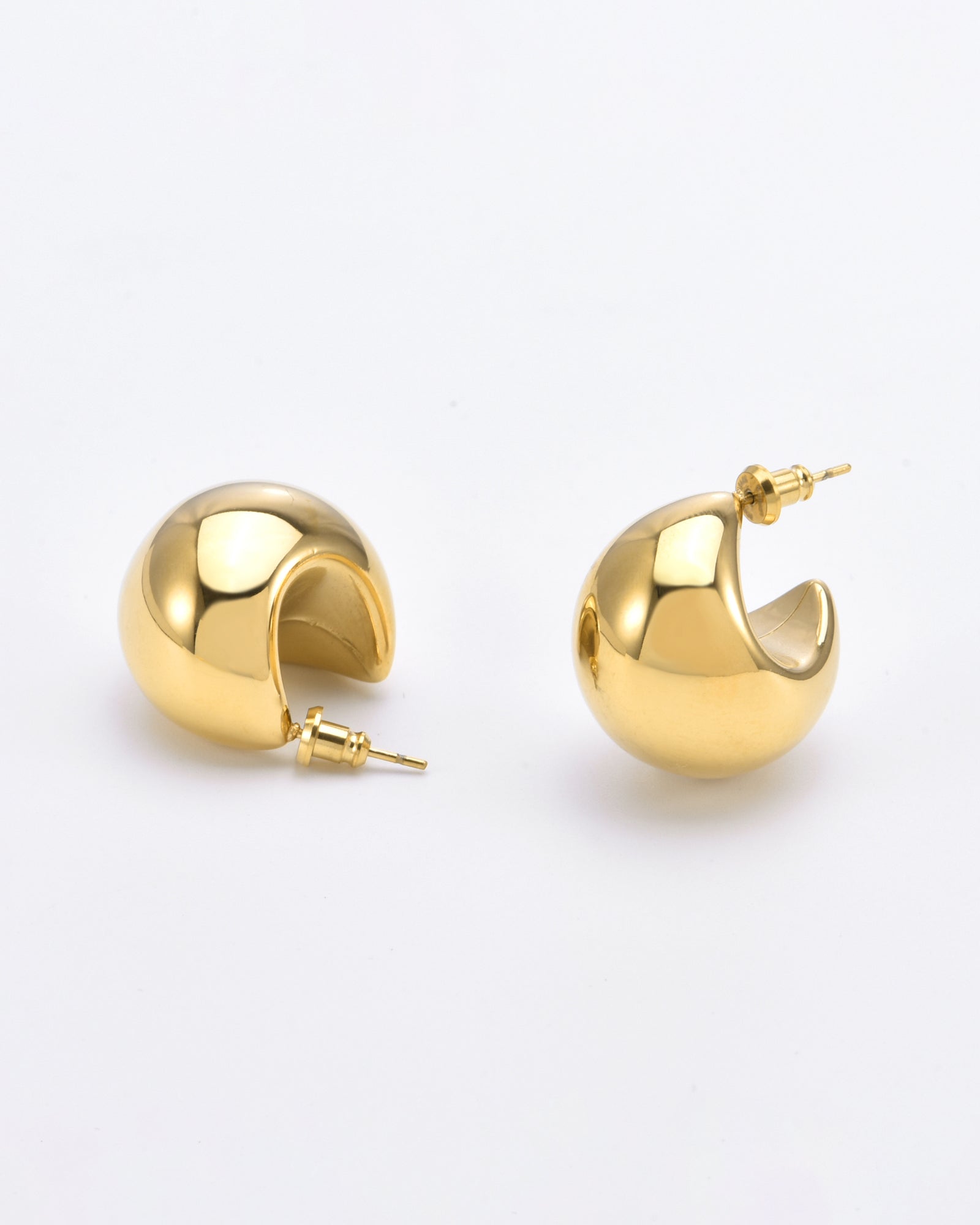 A pair of small, polished 24k gold Orbit Earrings Gold from For Art's Sake® is displayed against a plain white background. The earrings have a thick, rounded design and are slightly open with post-back closures.