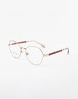 A pair of Orchard eyeglasses by For Art's Sake® featuring thin, 18-karat gold-plated metal frames. The temples are partly brown with a slightly translucent finish at the ends. The nose pads are clear, and the glasses are set against a white background.