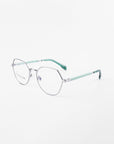 A pair of Orchard by For Art's Sake® eyeglasses with hexagonal silver frames and clear, prescription lenses. The arms of the glasses are light green, creating a modern and stylish look. The background is plain white, highlighting the glasses.