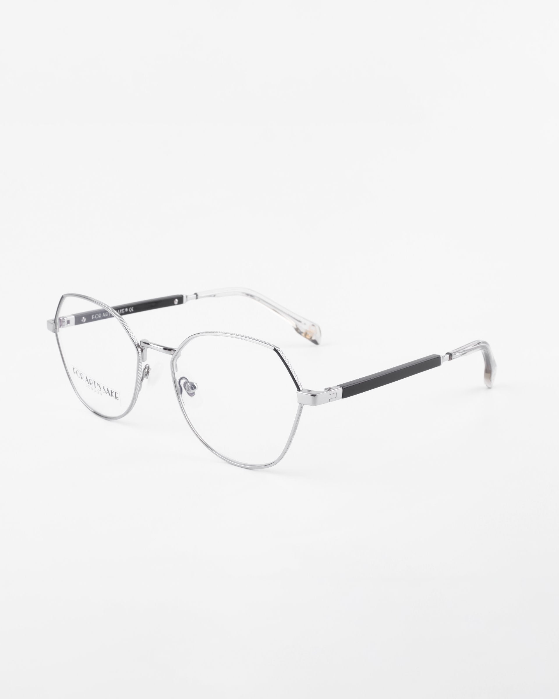 A pair of Orchard eyeglasses by For Art&#39;s Sake® with a sleek, modern design, featuring silver metal frames and thin black arms. The oval-shaped, rimless lenses are prescription lenses with a blue light filter. The Orchard glasses are set against a plain white background.