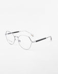 A pair of Orchard eyeglasses by For Art's Sake® with a sleek, modern design, featuring silver metal frames and thin black arms. The oval-shaped, rimless lenses are prescription lenses with a blue light filter. The Orchard glasses are set against a plain white background.