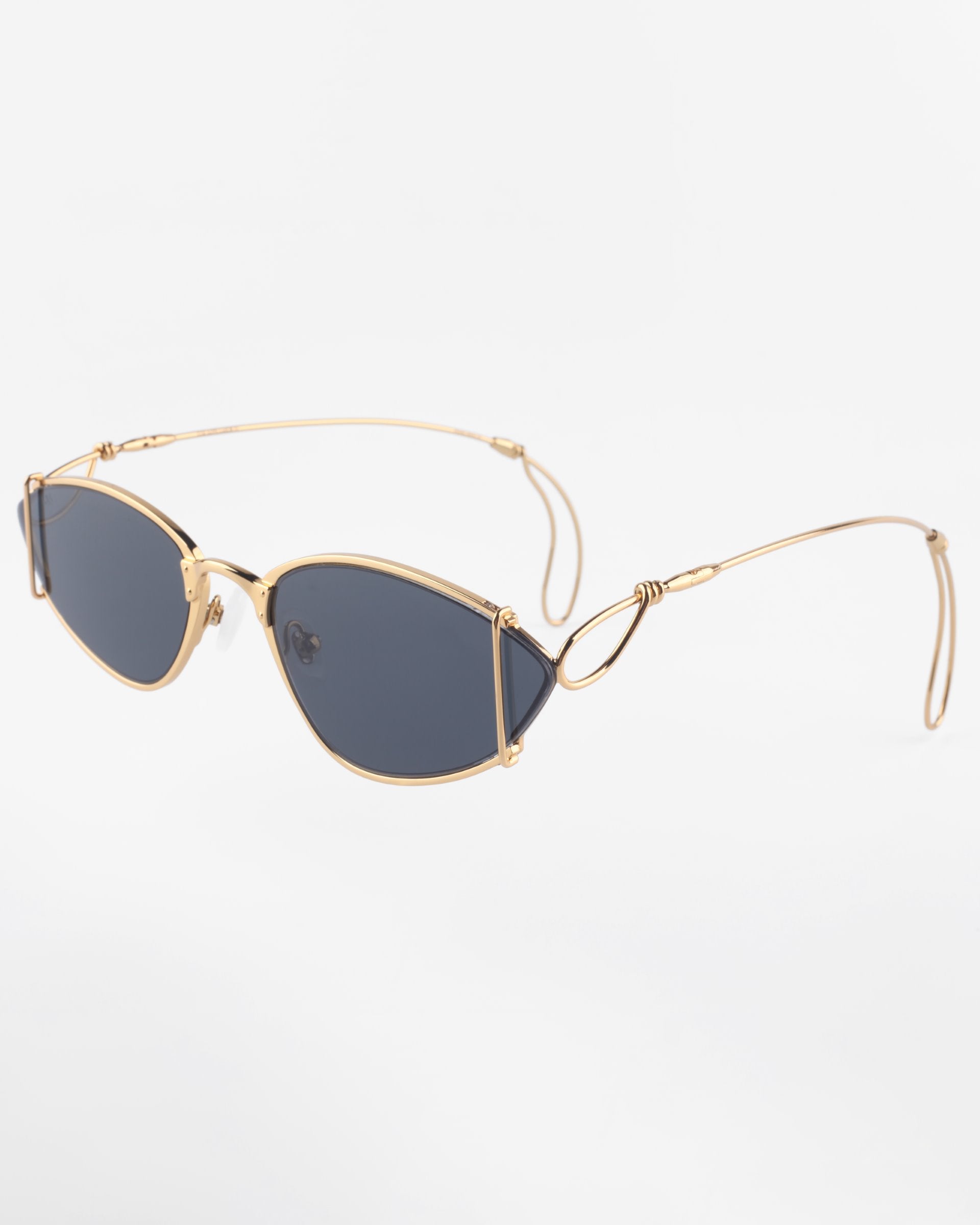 A pair of sleek, gold-plated stainless steel sunglasses with dark, narrow oval lenses and thin, wire-like arms. The minimalist design, 100% UVA &amp; UVB protection, and anti-reflective coating give these Ornate sunglasses by For Art&#39;s Sake® a modern, stylish appearance against a plain white background.
