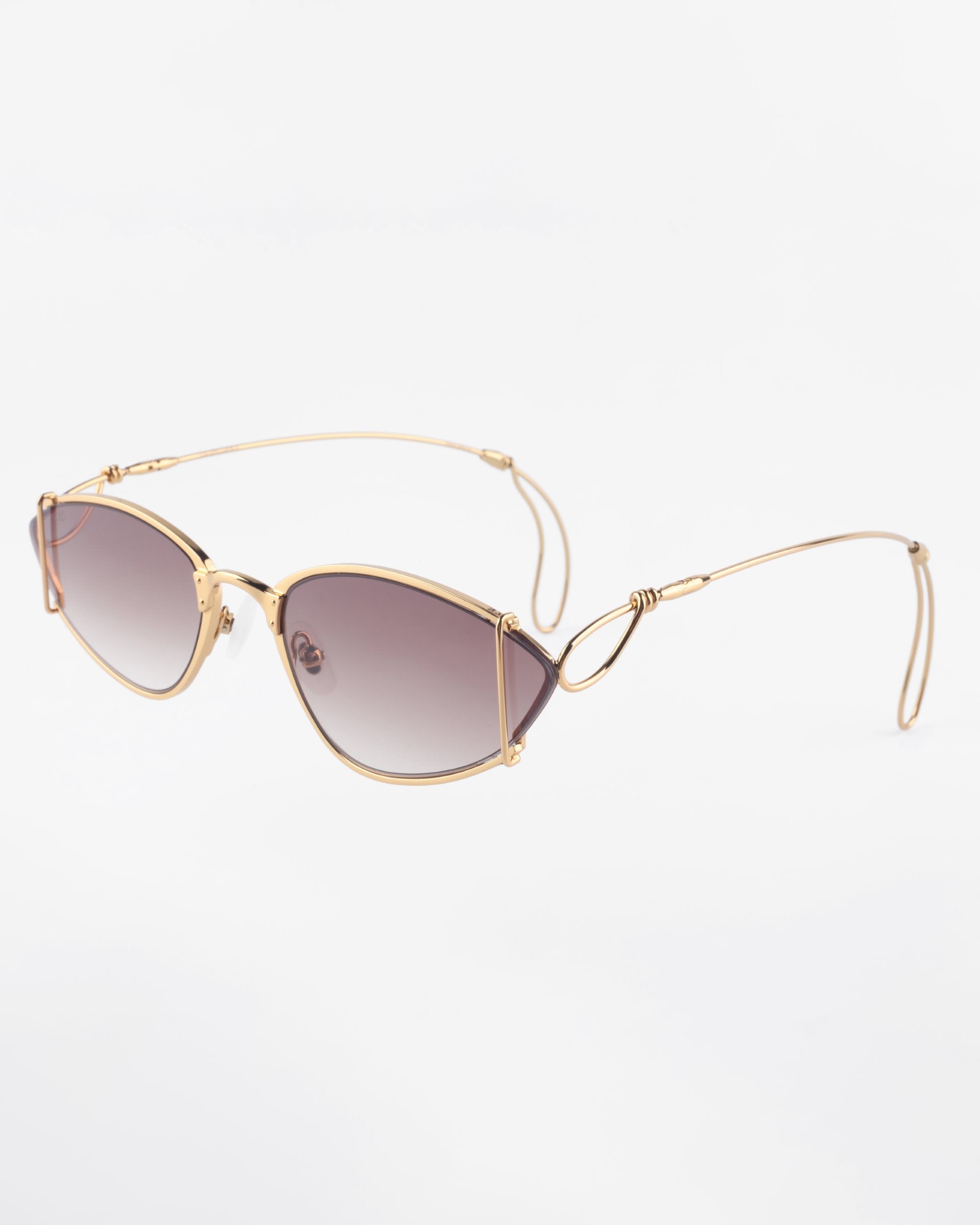 A pair of stylish For Art's Sake® Ornate sunglasses with thin, 18-karat gold-plated frames and an intricate double-bridge design. The ultra-lightweight Nylon lenses are tinted in a gradient from dark at the top to lighter at the bottom, offering 100% UVA & UVB protection. The temples have a sleek curve, ending in curved earpieces.