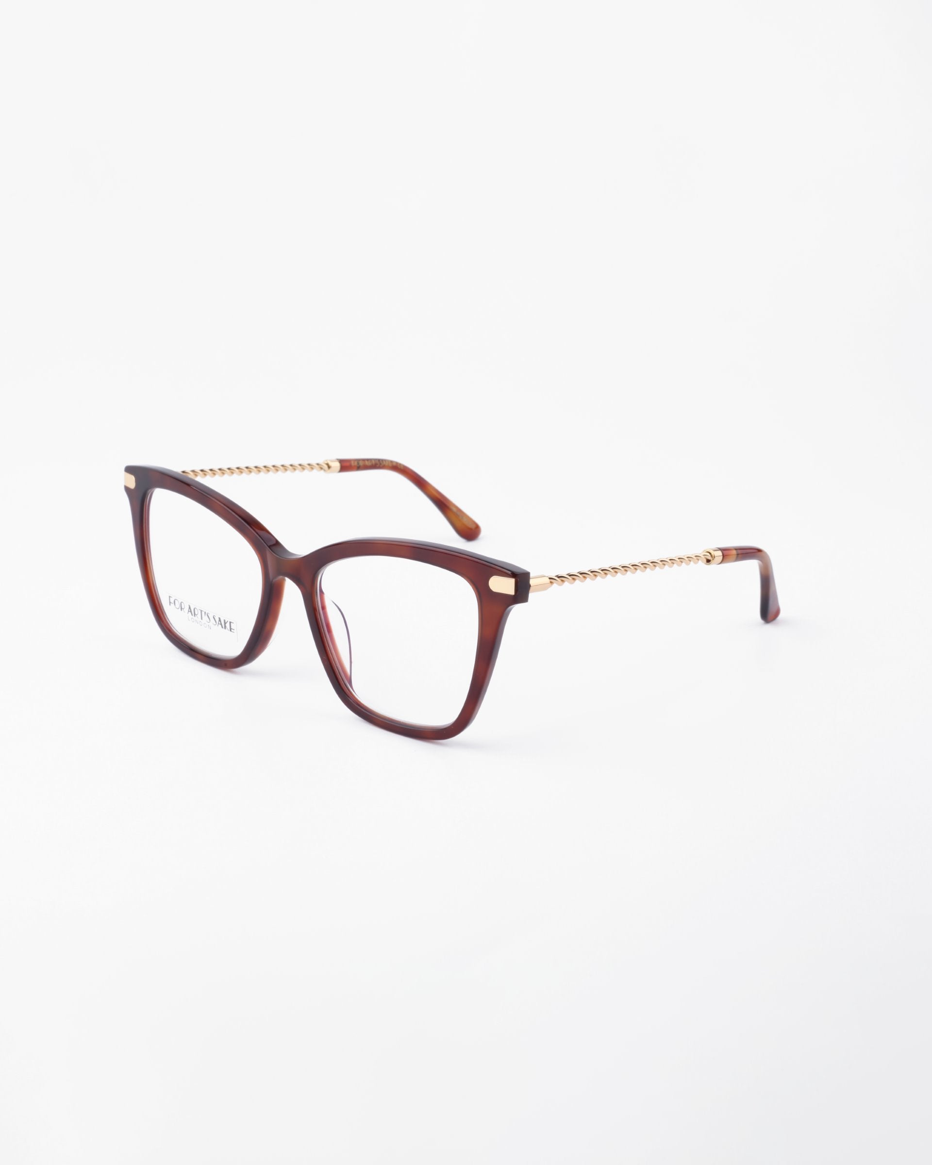 A pair of Paris Two eyeglasses by For Art&#39;s Sake® with a tortoiseshell frame and gold temples is displayed against a white background. The temples have a chain-like design, the clear lenses offer UV protection, and are suitable for prescription use. The brand &quot;For Art&#39;s Sake®&quot; is visible on the lens.