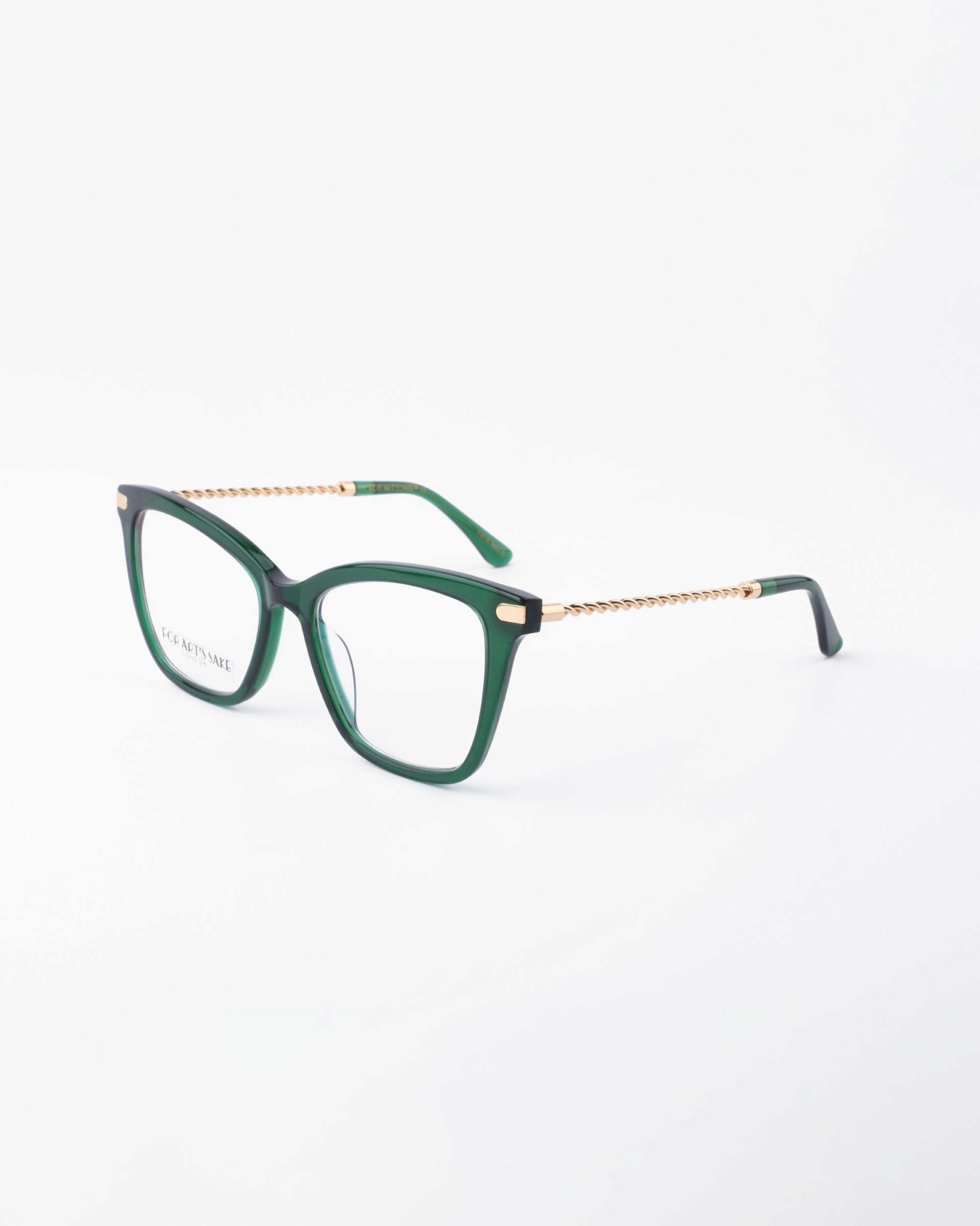 A pair of green Paris Two eyeglasses with square-shaped frames and gold braided metal arms by For Art&#39;s Sake® is displayed against a plain white background. The brand name is visible on the left lens. Designed with both classic and modern elements in mind, these glasses also feature a blue light filter for added protection.