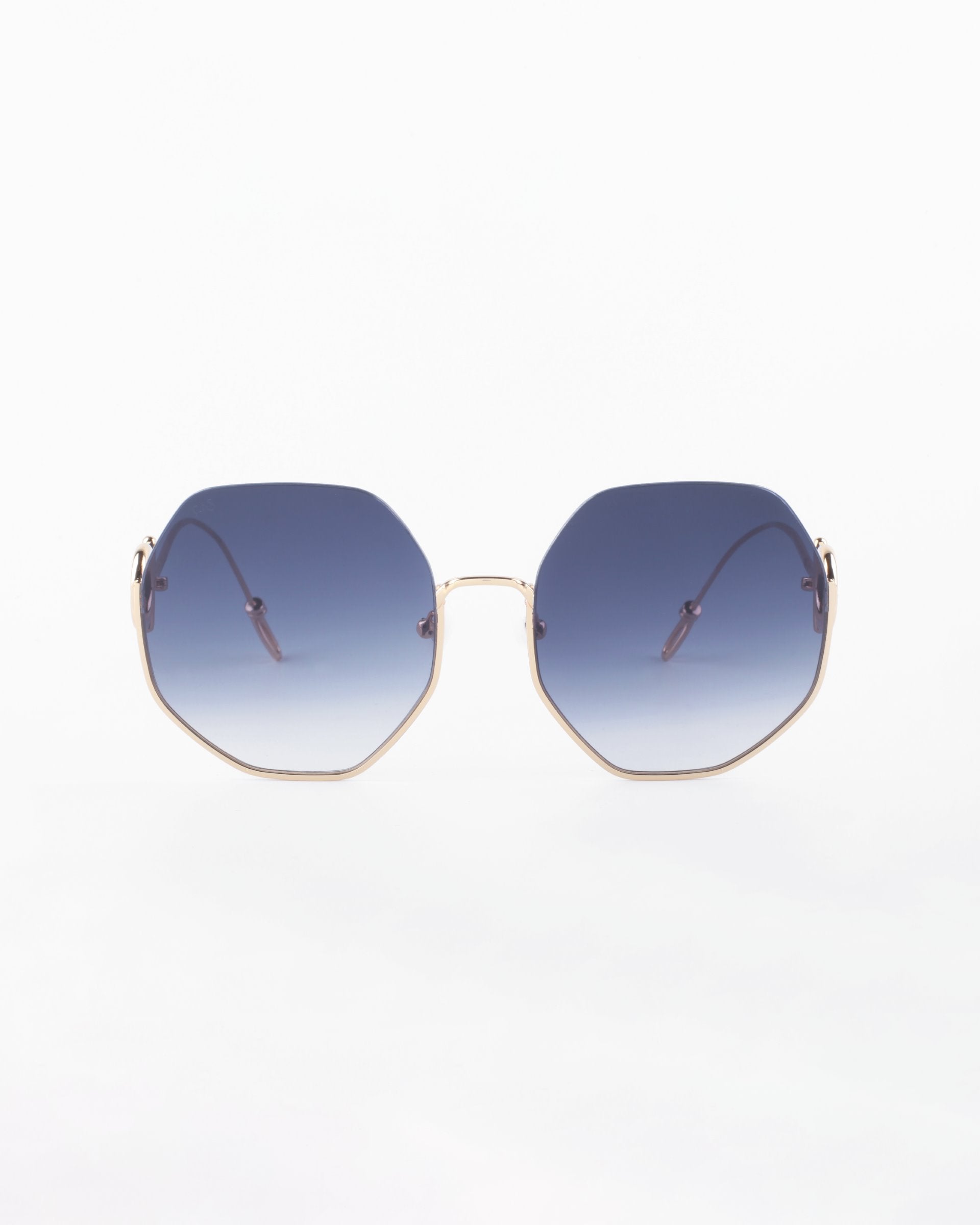 A pair of stylish, limited edition For Art&#39;s Sake® Palace sunglasses with blue gradient hexagonal lenses and thin, 18-karat gold-plated frames is displayed against a plain white background. The design is modern and chic, offering both a fashionable look and UVA &amp; UVB protection.