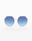 A pair of For Art's Sake® Palace UVA & UVB-protected sunglasses with 18-karat gold-plated wire frames and blue-tinted hexagonal lenses is centered against a white background. The temples extend from the frames to thin, curved earpieces. The overall design is modern and minimalist.