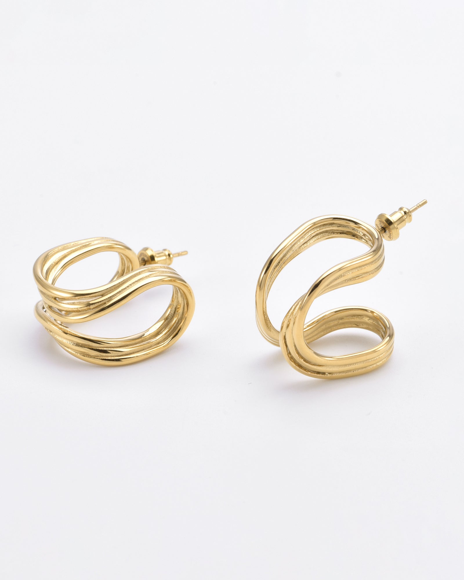 A pair of 24k gold, twisted hoop earrings with a smooth and shiny finish. Each Portrait Earrings Gold by For Art's Sake® features a unique, wavy design with an interwoven loop pattern. The earrings have standard posts for pierced ears and are displayed against a plain white background.