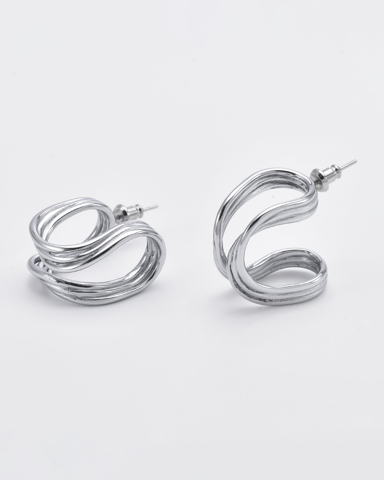 A pair of modern silver earrings with a looping, abstract design. The earrings have a glossy finish and are displayed against a plain white background. Each earring consists of a continuous curved shape with an attached stud for securing to the ear, reminiscent of **Portrait Earrings Silver by For Art's Sake®**.