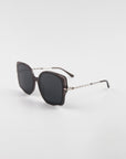 A pair of stylish, oversized square Fahrenheit sunglasses with dark lenses and thin, intricate 18-karat gold-plated arms by For Art's Sake®, isolated on a white background.