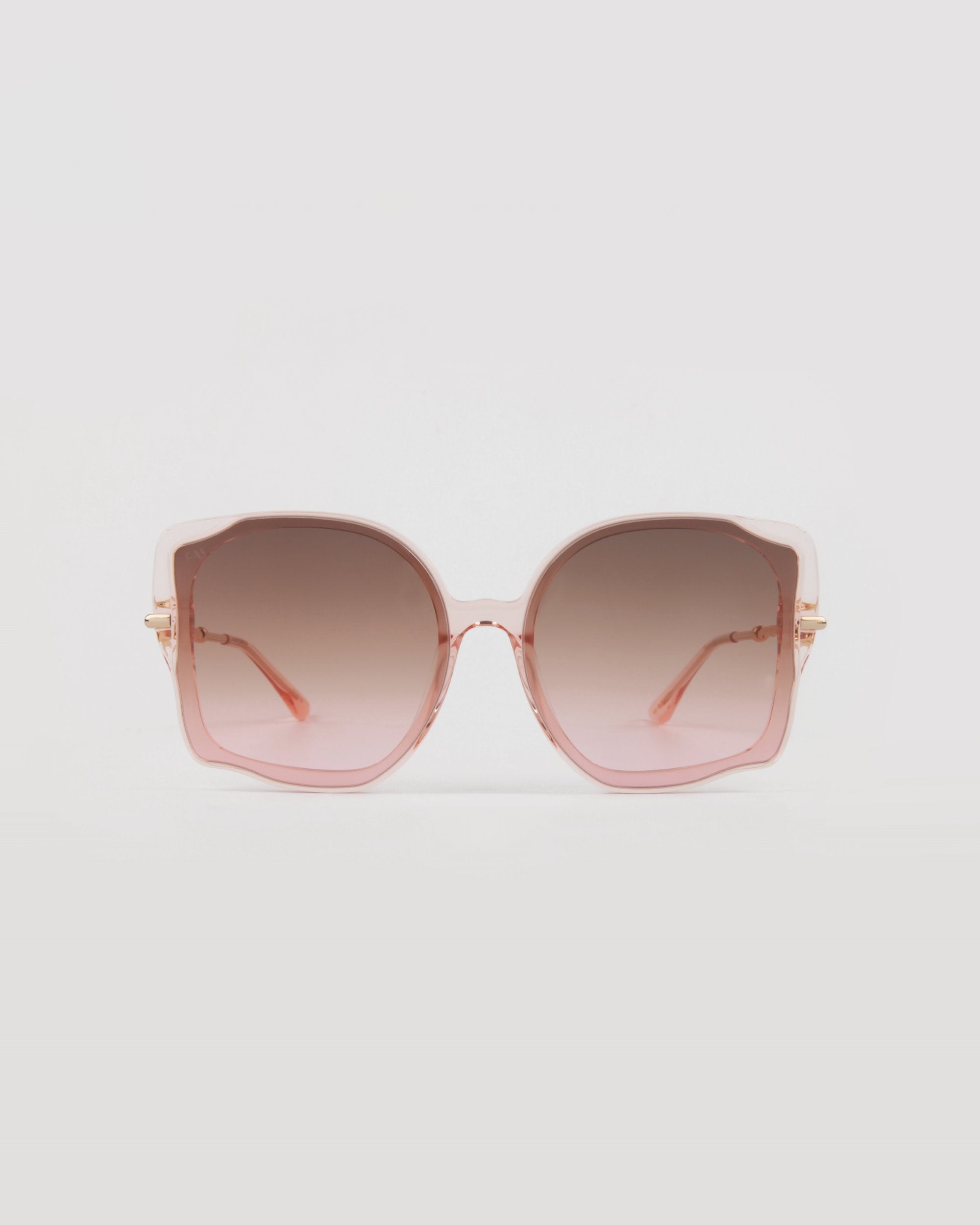A pair of stylish, oversized frame sunglasses with pale pink handmade acetate frames and gradient lenses, transitioning from darker at the top to lighter at the bottom, set against a plain white background. These are the Fahrenheit by For Art&#39;s Sake®.