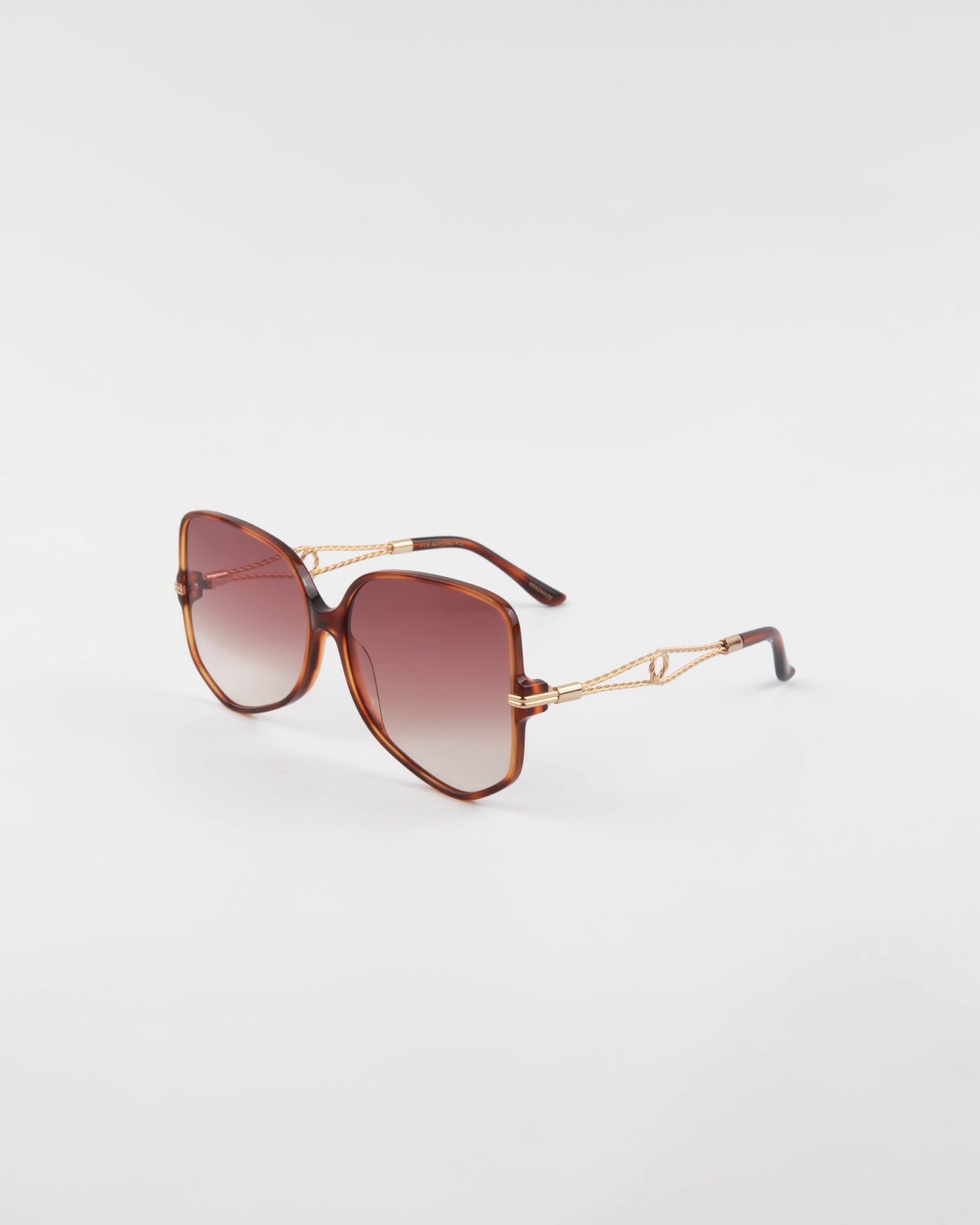 A pair of stylish, oversized Voyager sunglasses with gradient lenses and gold-plated frames by For Art&#39;s Sake®. The translucent brown temples and arms feature elegant gold accents. Handmade acetate eyewear offering optimal UVA &amp; UVB protection, showcased against a plain, white background.