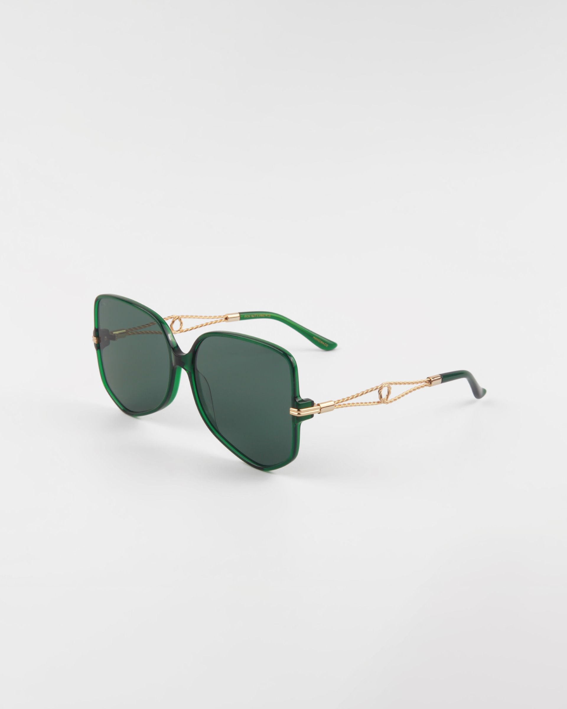 A pair of stylish handmade acetate eyewear with green-framed sunglasses featuring rectangular lenses and gold-accented temple arms, offering UVA &amp; UVB protection, set against a white background. The Voyager by For Art&#39;s Sake®.