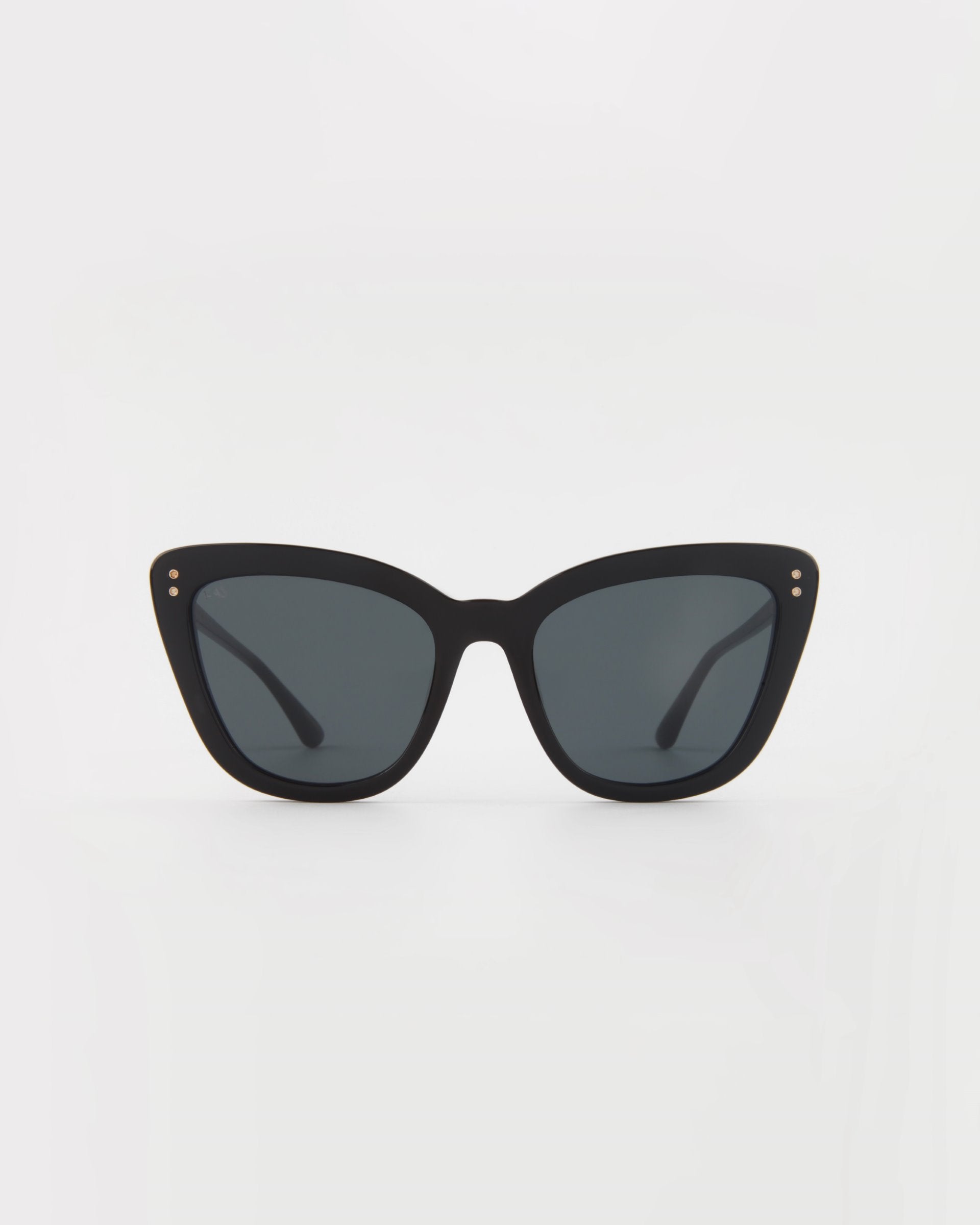 A pair of For Art&#39;s Sake® Ice Cream handmade acetate cat-eye sunglasses with dark tinted lenses is centered against a white background. The frame features small gold accents at the corners of the lenses, ensuring both style and UVA &amp; UVB protection.