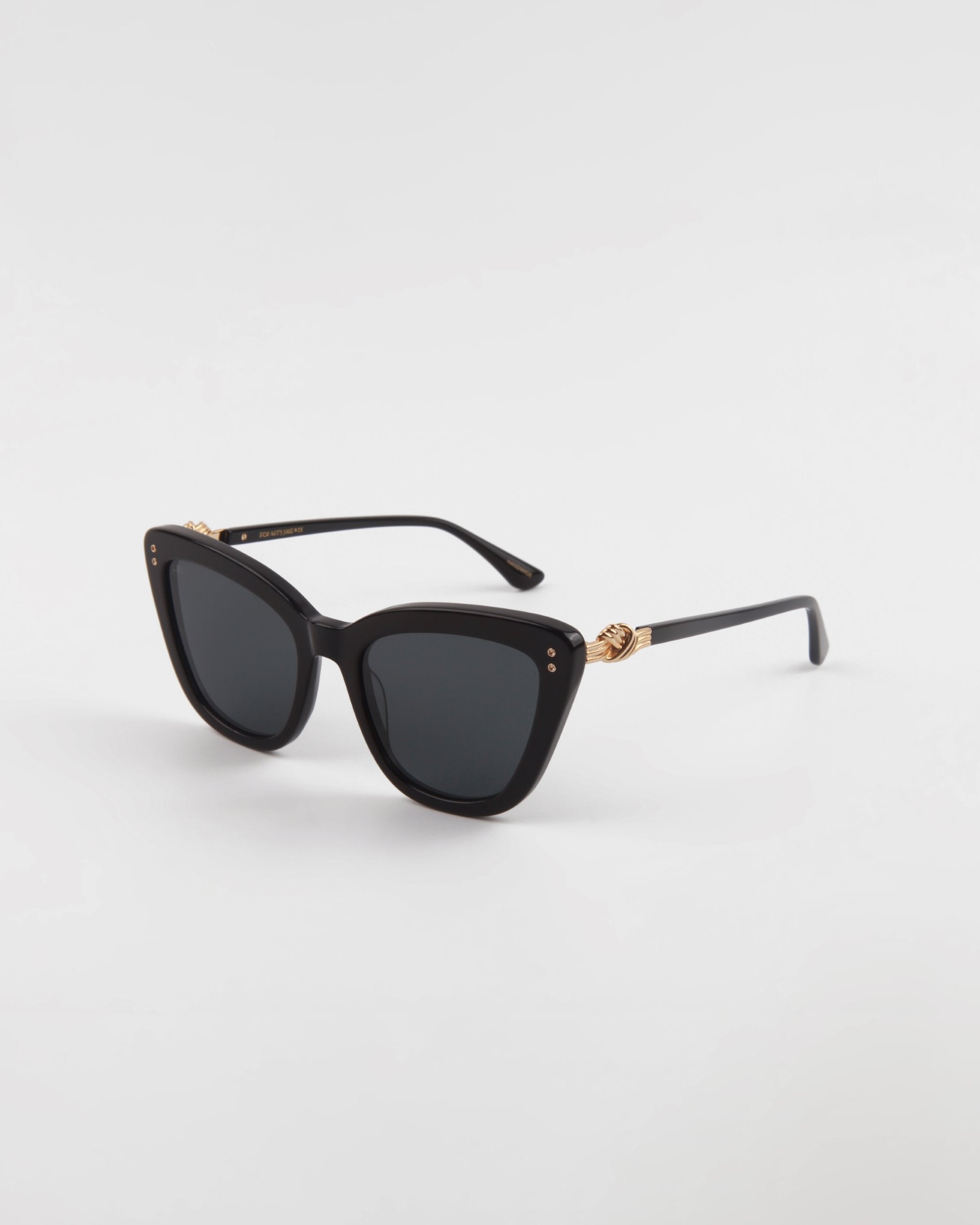 A pair of black, handmade acetate cat-eye **Ice Cream** sunglasses with dark lenses and gold embellishments on the arms from **For Art&#39;s Sake®.** The **Ice Cream** sunglasses offer UVA &amp; UVB protection and are set against a plain white background, highlighting their sleek and stylish design.
